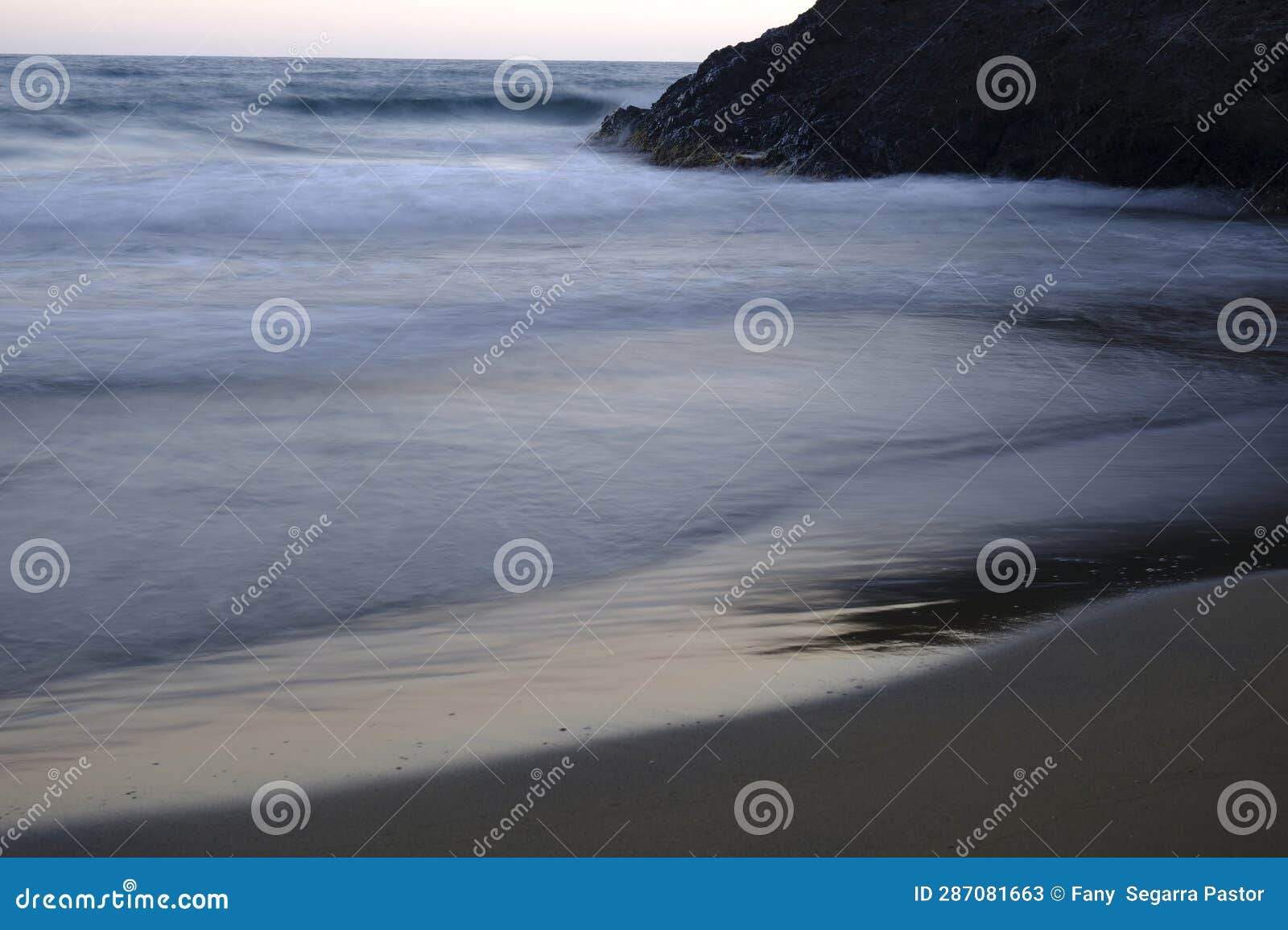 the waves calmly approach the shore of the beach,