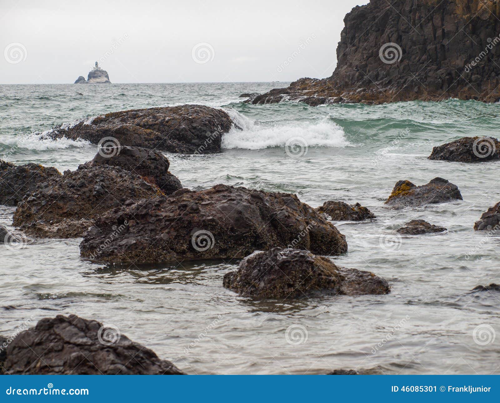 waves crashing on rocks with tillamook lighthouse