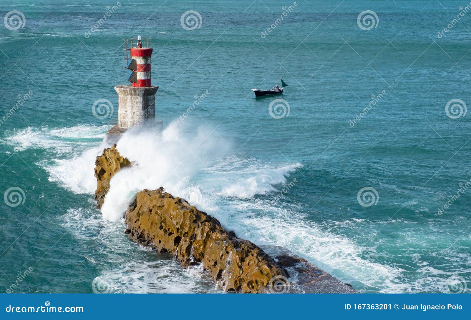 waves, fishing boat and lighthouse in the bay of pasaia, euskadi