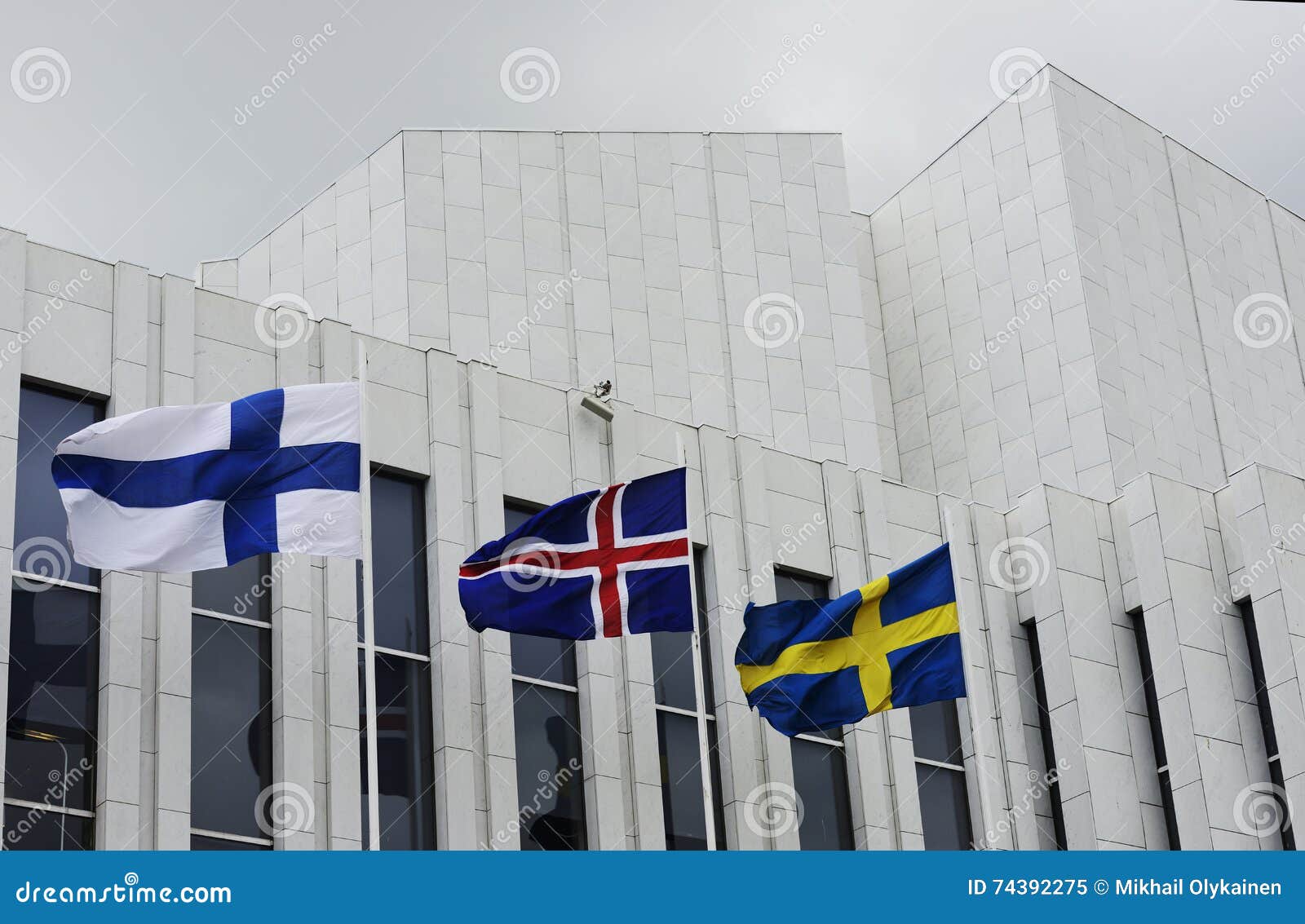 waving finnish, swedish, icelandic flags against of finlandia ha