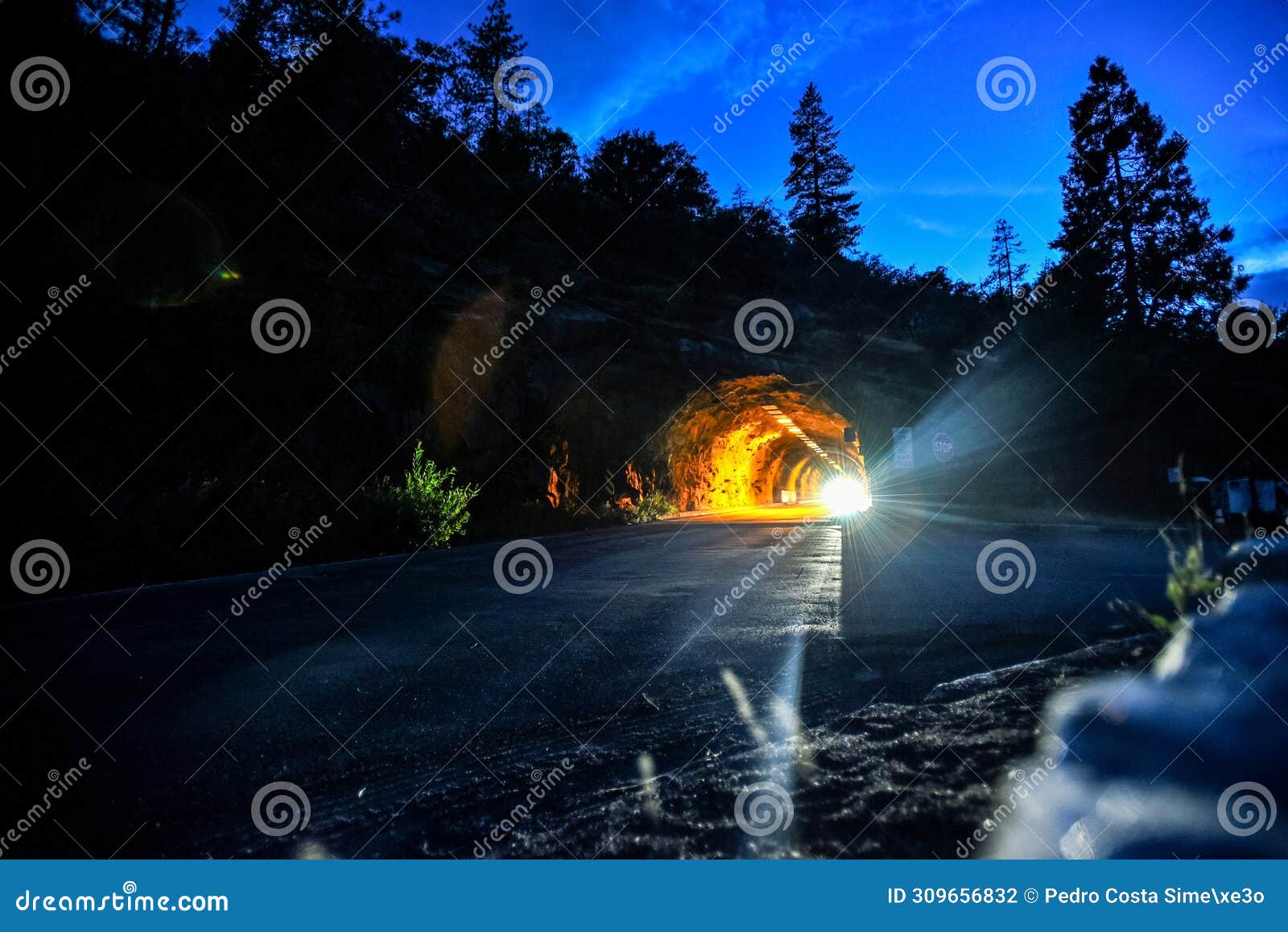 lights of a car leaving the wawona tunnel in the evening - yosemite national park, california