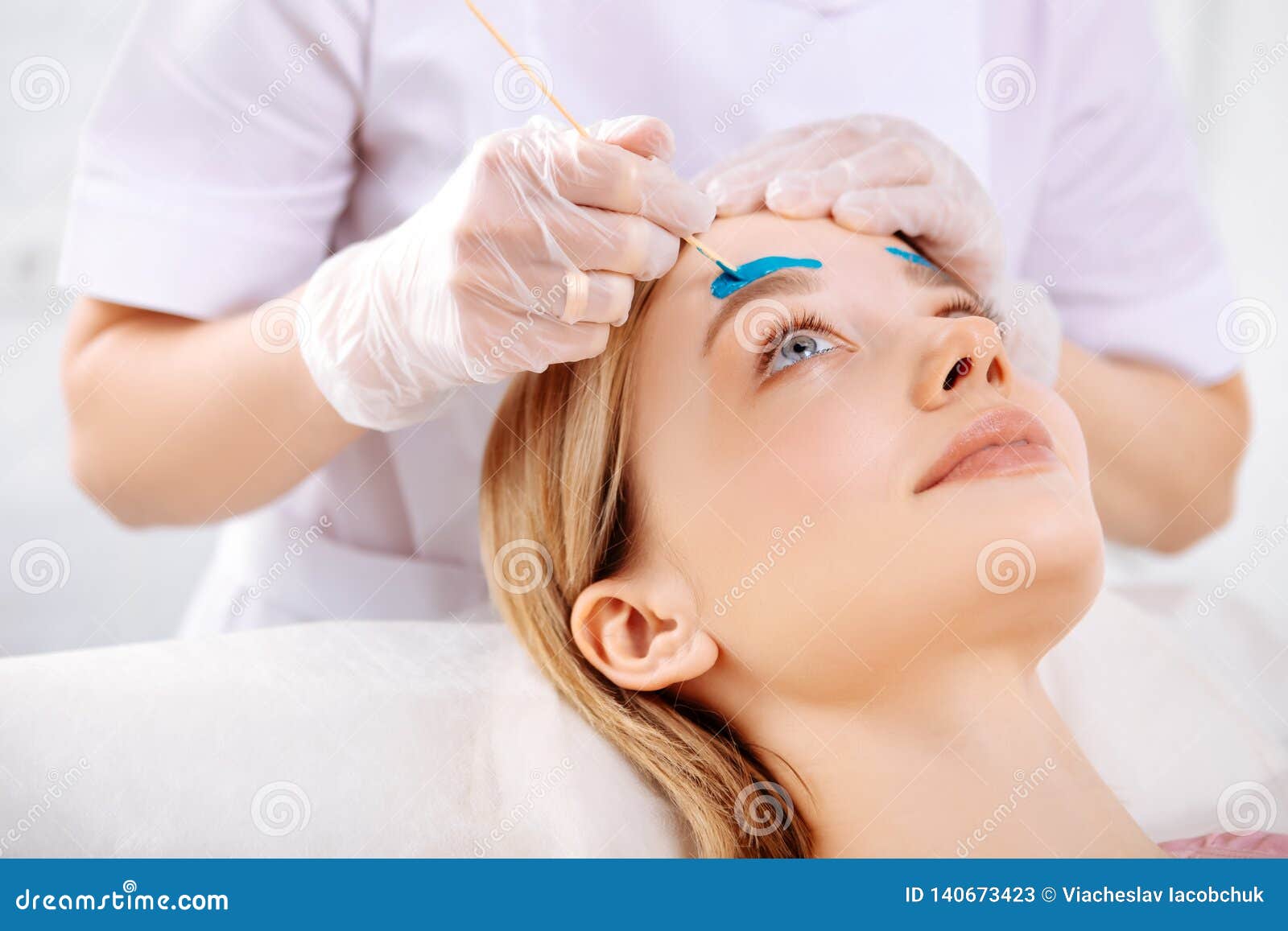 Specialist Wearing Gloves Waxing Forehead of Beautiful Client Stock