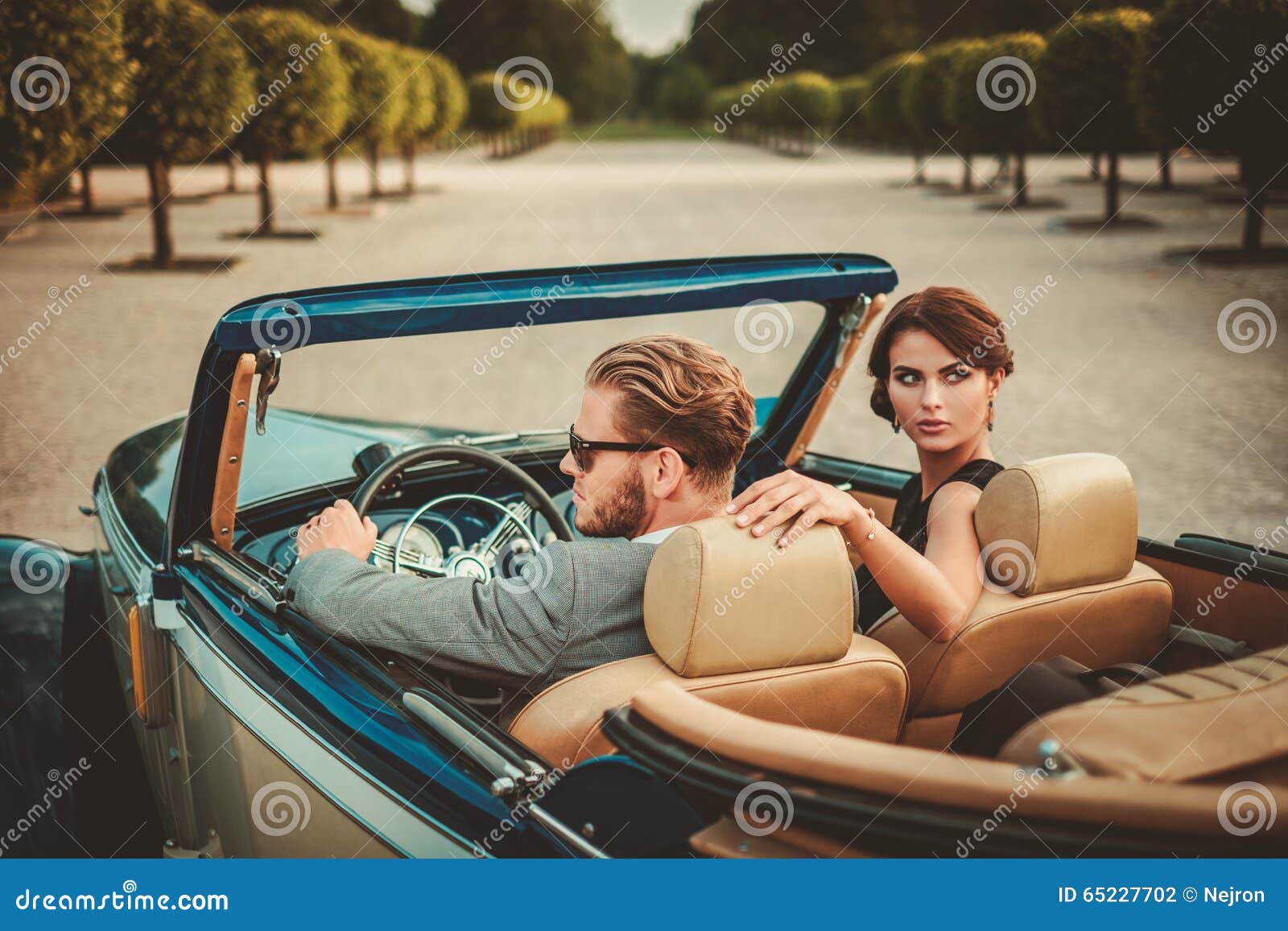 wealthy couple in classic convertible