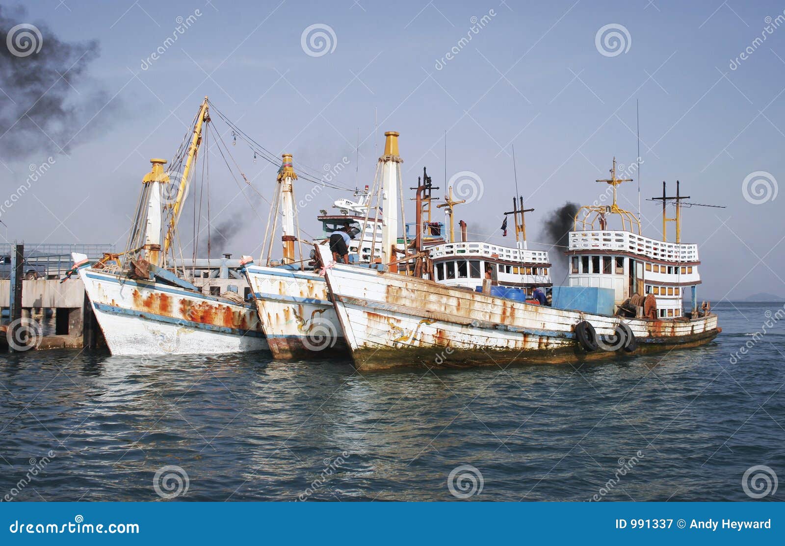 Scenic view of three old weathered wooden boats moored by pier of 