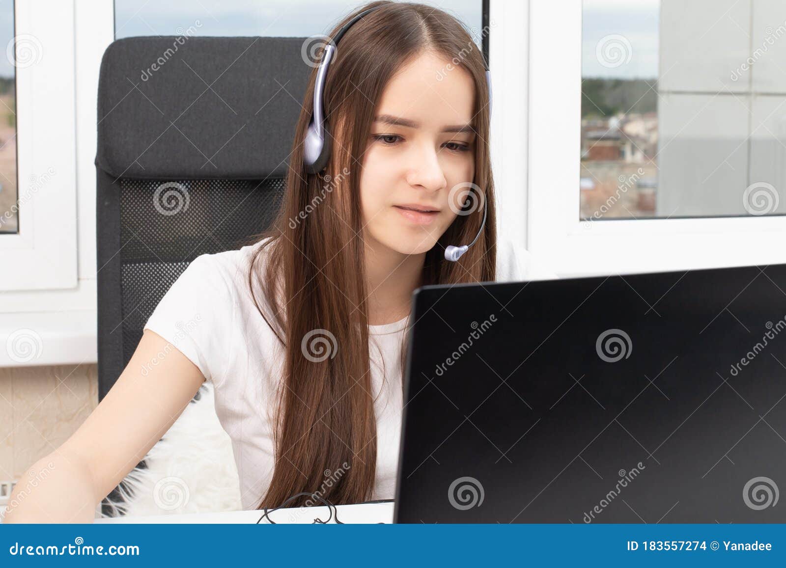 inar. Girl in Headphones with a Microphone in Front of a Laptop