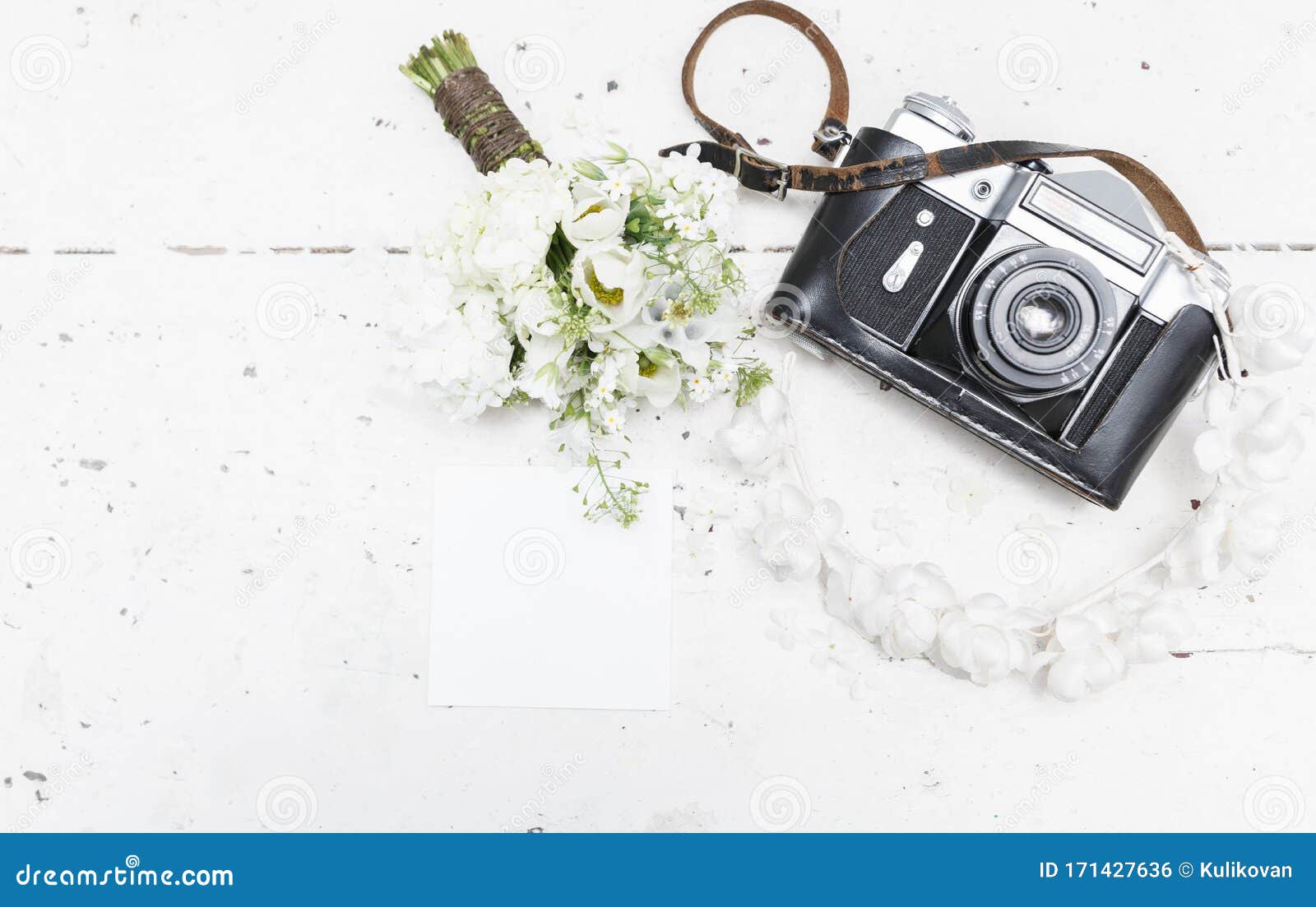 the bride`s bouquet with vintage photo camera and bridal wreath on wooden table.