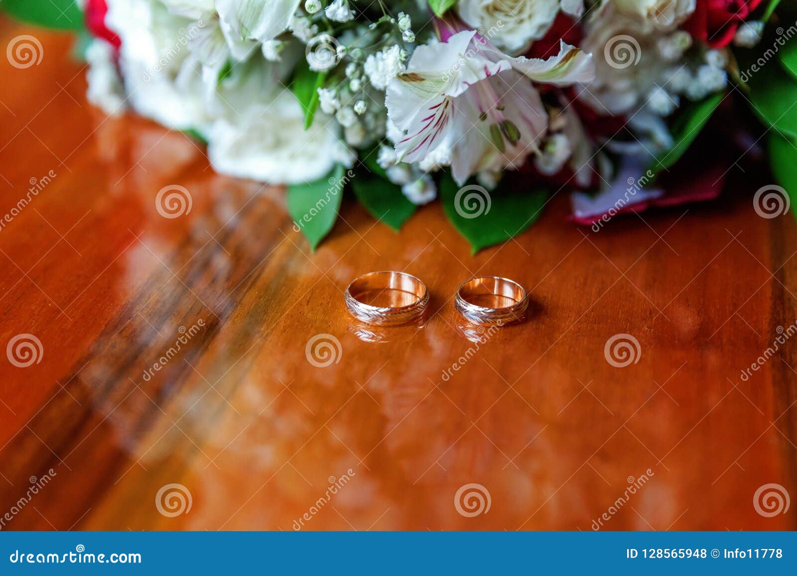 Wedding Rings Lie on Wooden Surface Against Background of Bouquet of ...