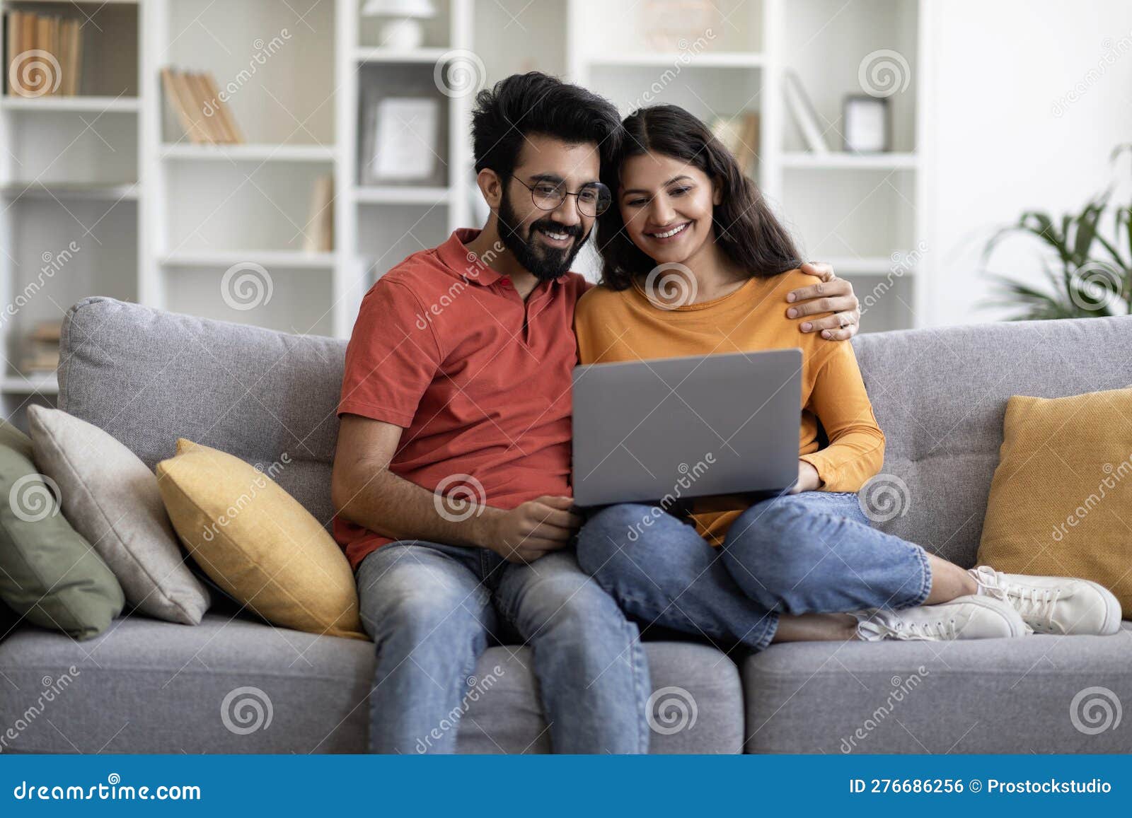 weekend passtime. happy indian couple using laptop computer at home together