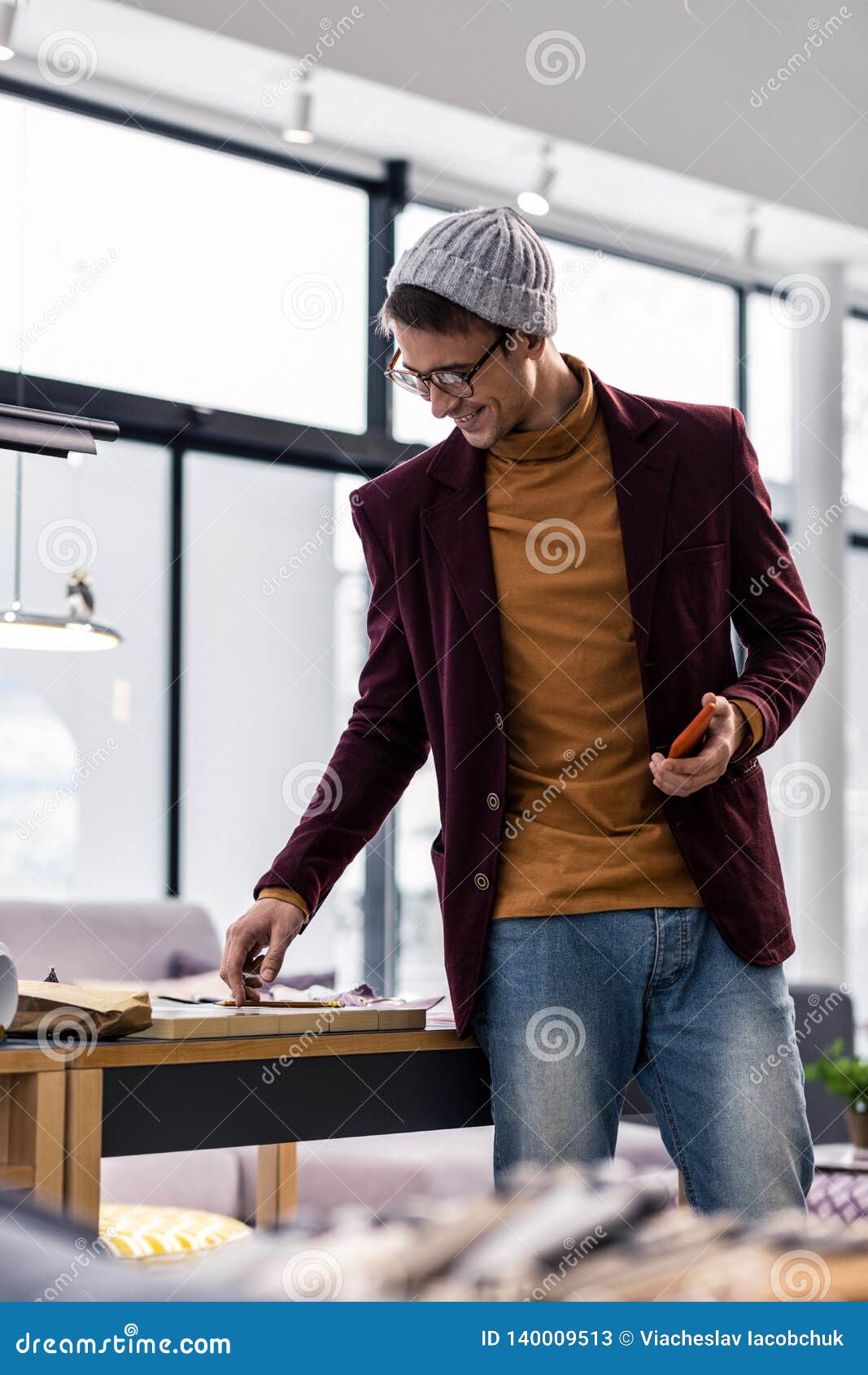 well-groomed trendy worn manager smilingly pointing at samples at desk