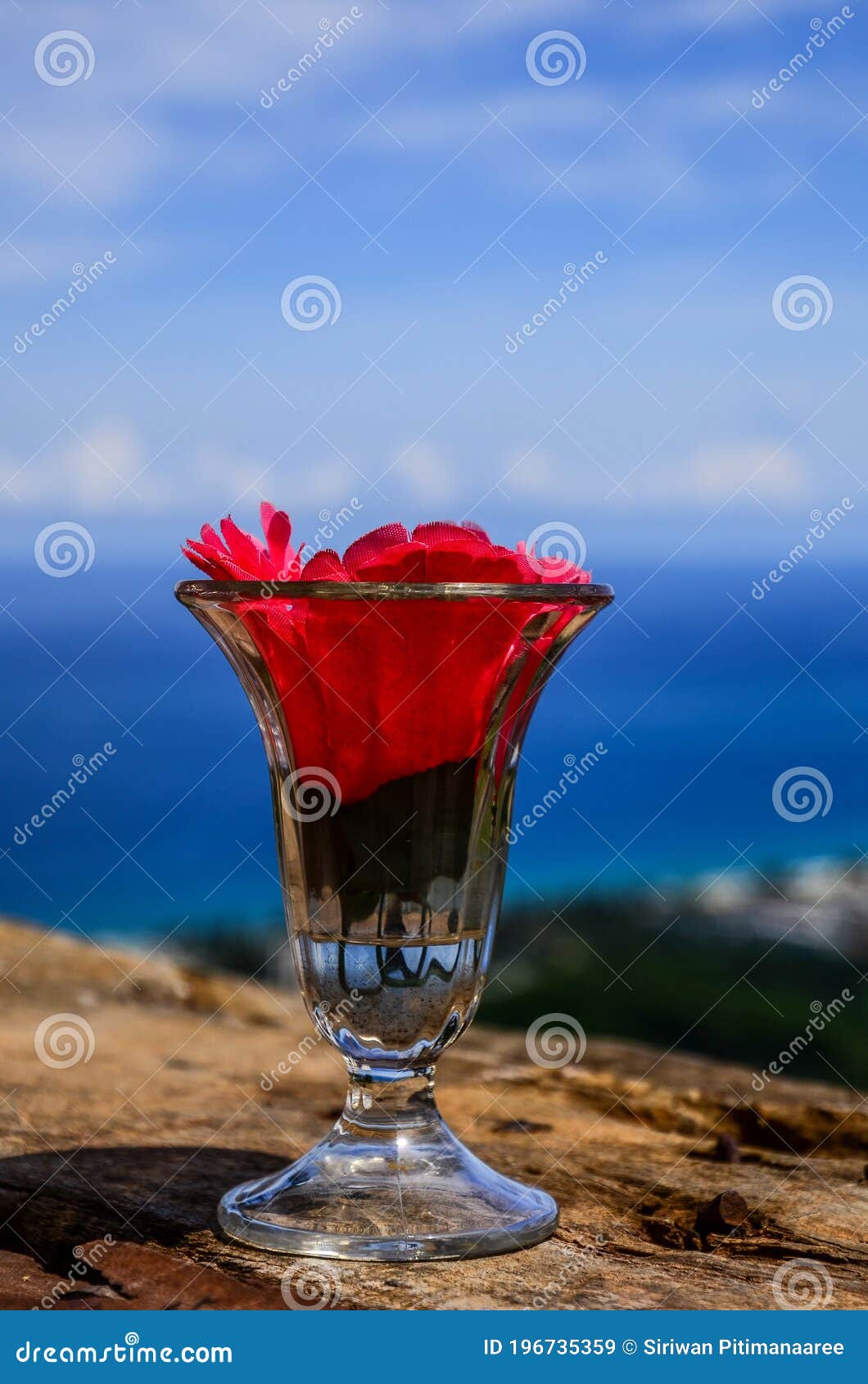 wellcome drink : cold water and red flower in clear glass on blue sky background