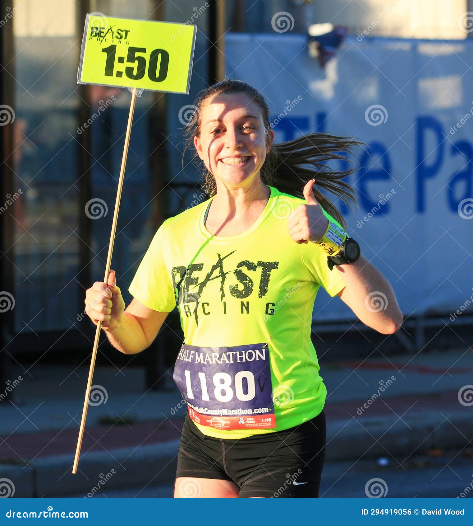 Female Half Marathon Pacer Carrying Sign And Giving A Thumbs Up female-half-marathon-pacer-carrying-sign-and-giving-a-thumbs-up