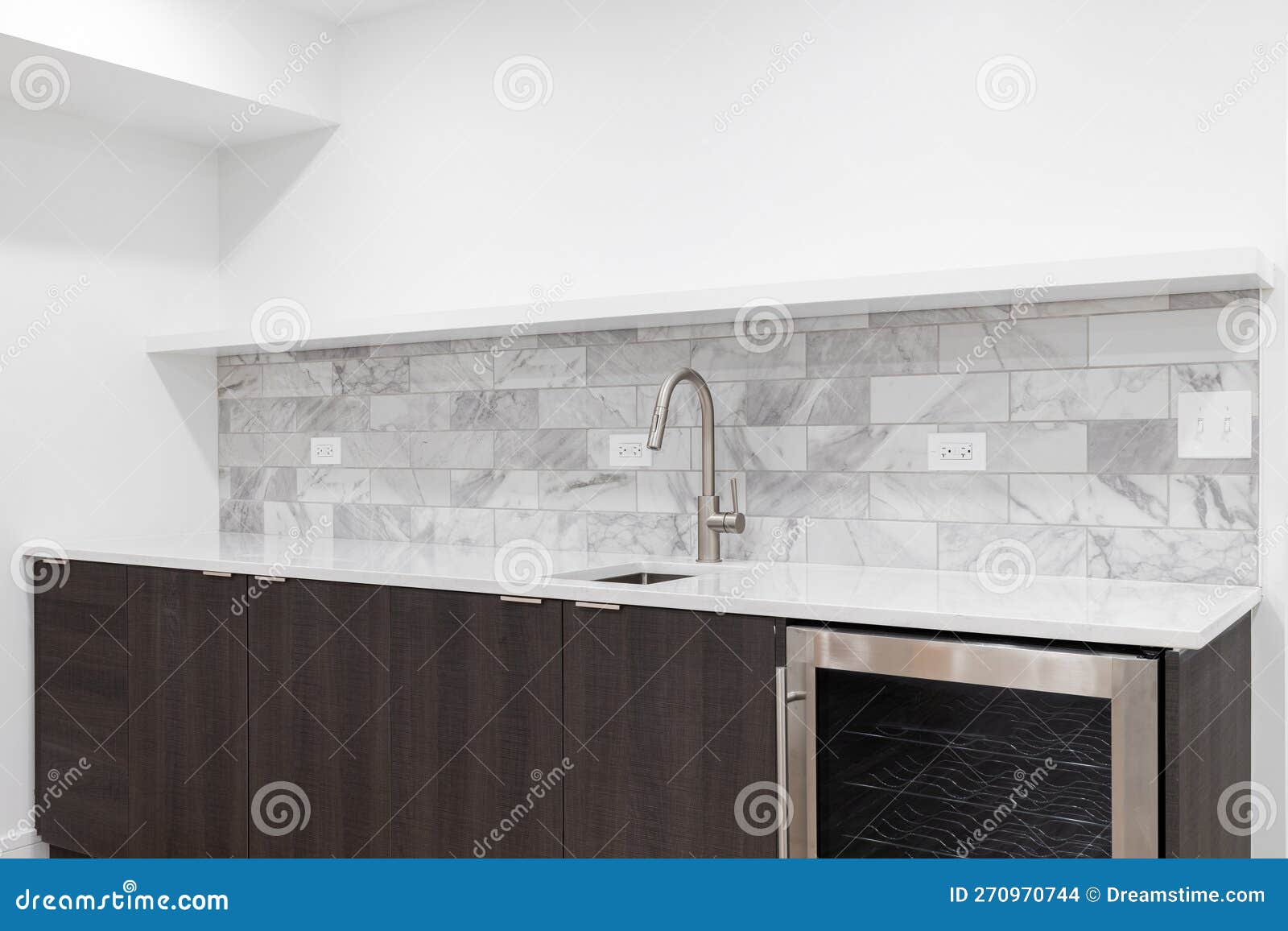 A Wet Bar with Wood and Marble Tile Backsplash. Stock Photo