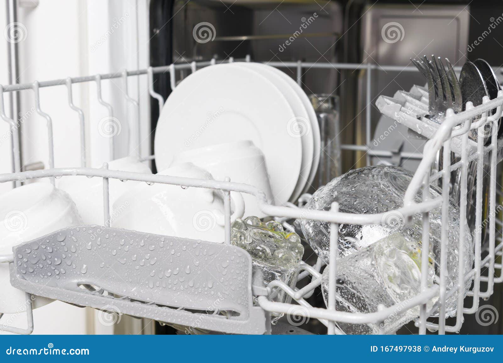 Wet Clean White Dishes and Cutlery are in the Dishwasher Stock Photo