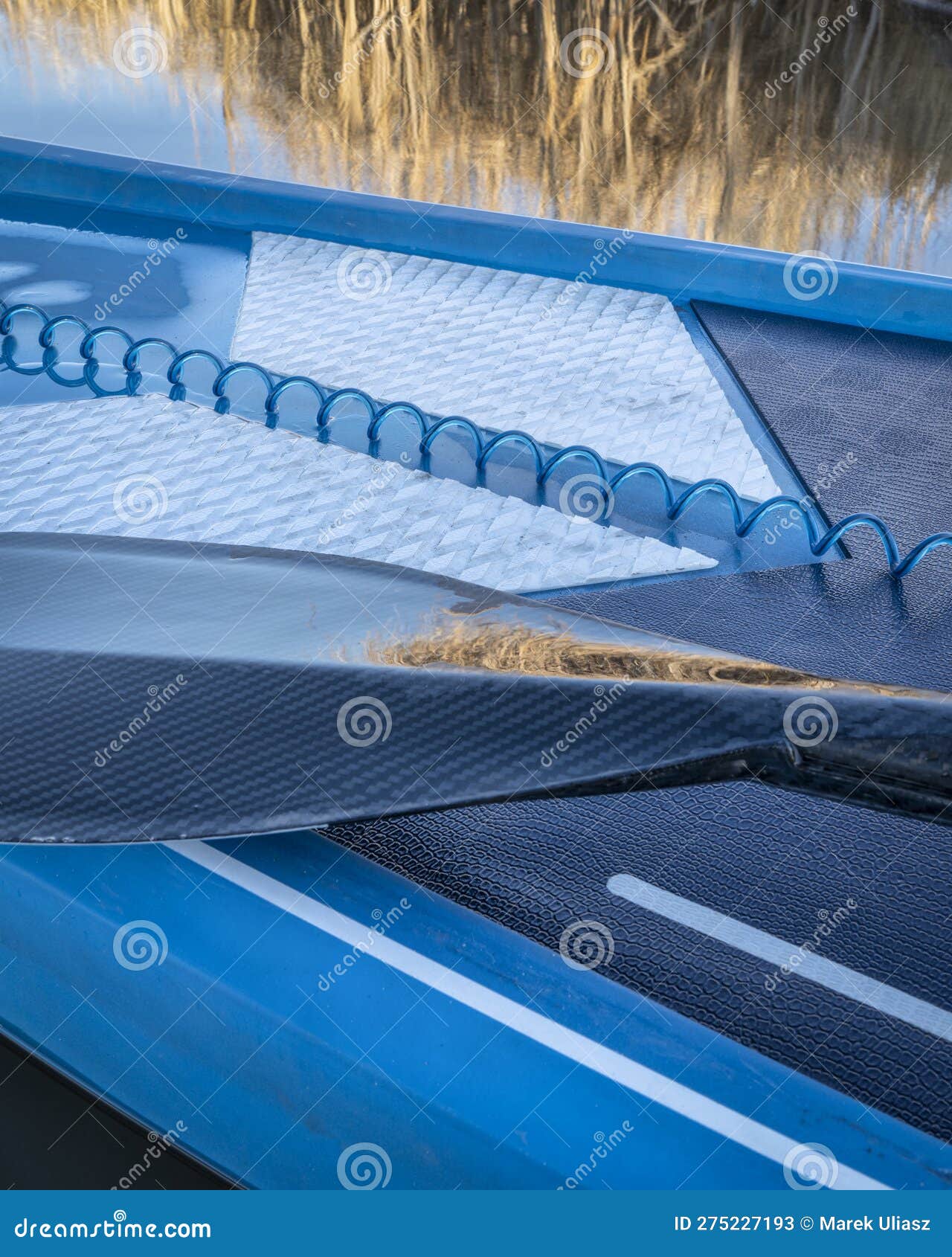 Paddle and a Coiled Safety Leash on a Deck of Stand Up Paddleboard