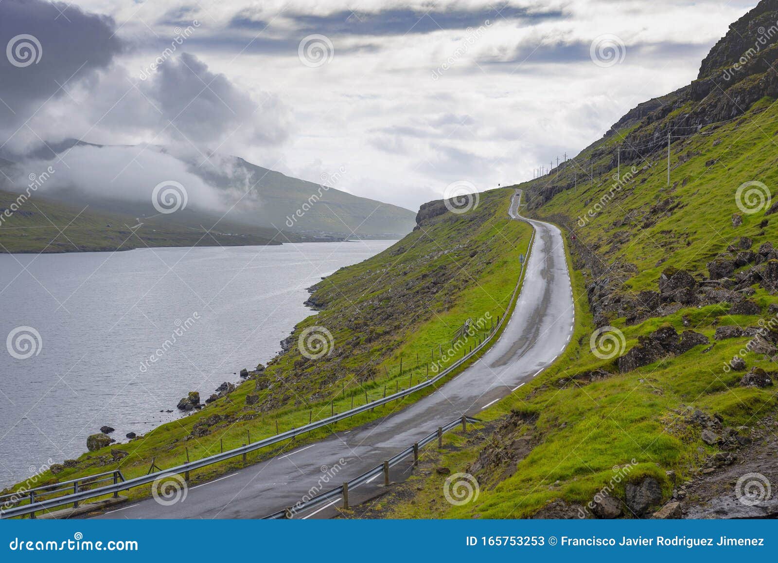 wet road bordering a lake in the faroe islands