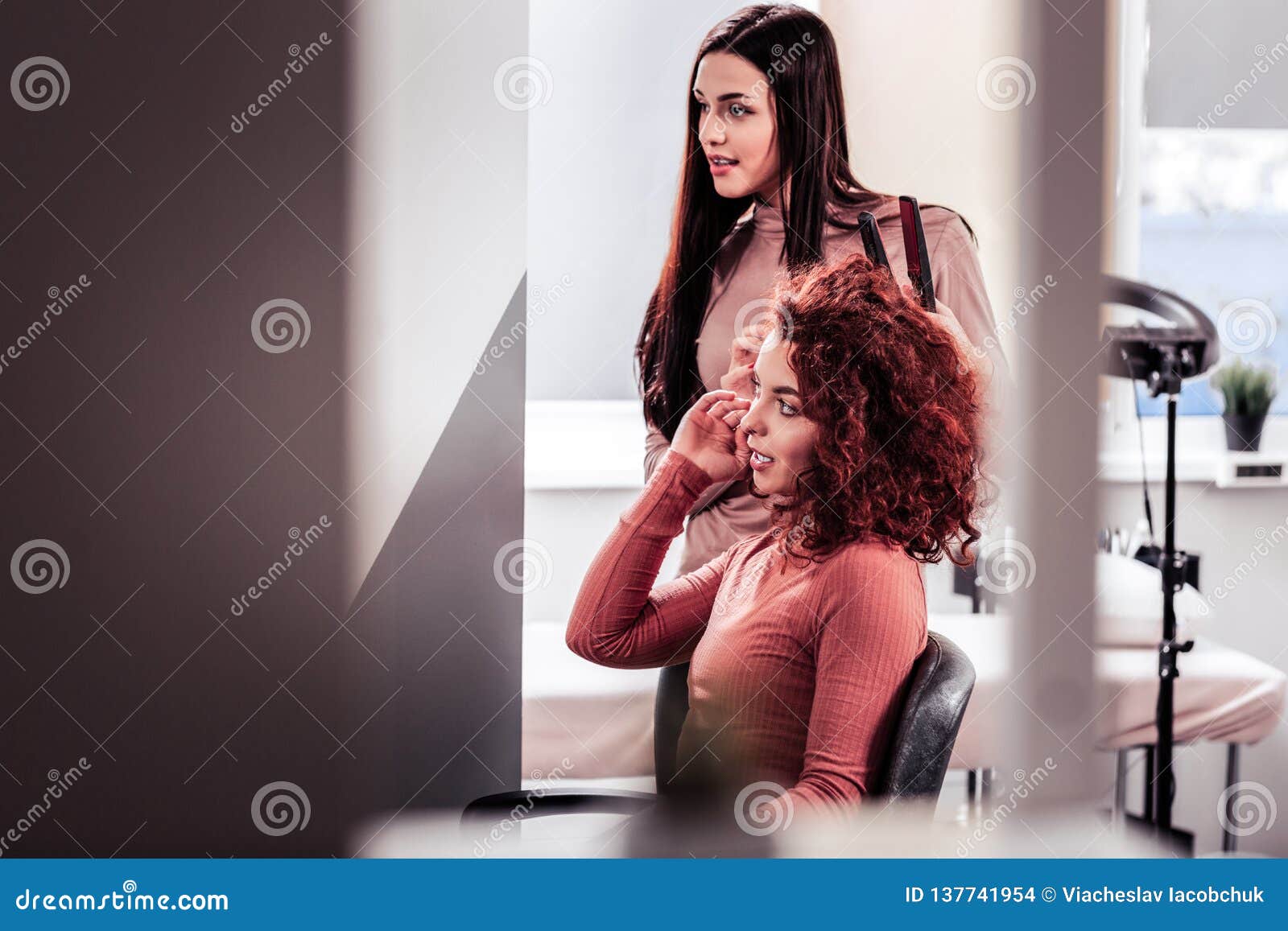 pleasant young woman speaking to her hair stylist