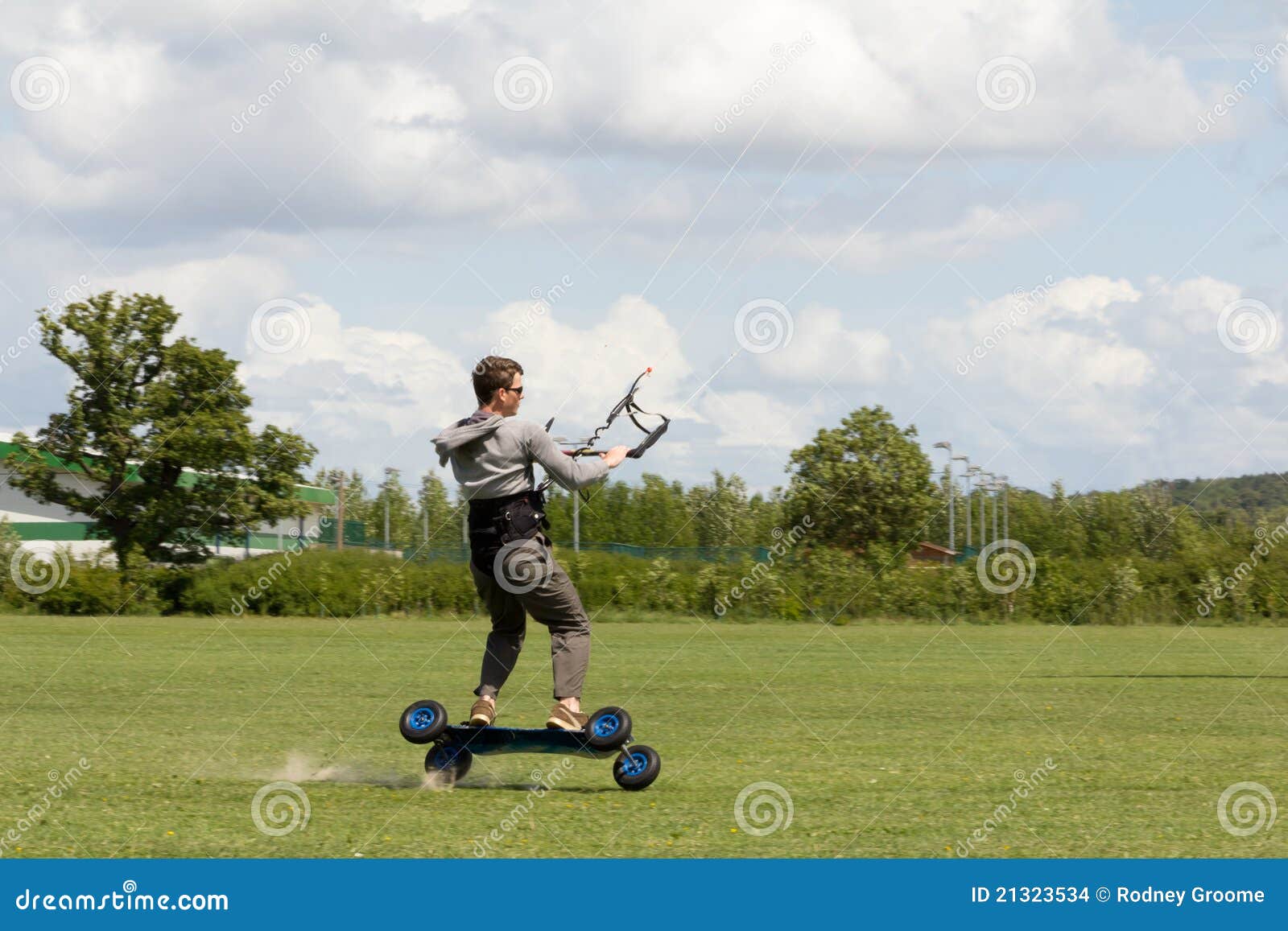 Wheelie-teenager kite boarding on two wheles on gr. Extreme sport kit boarding,teenage boy stands on his board on two wheels as his kite speeds him over grass.