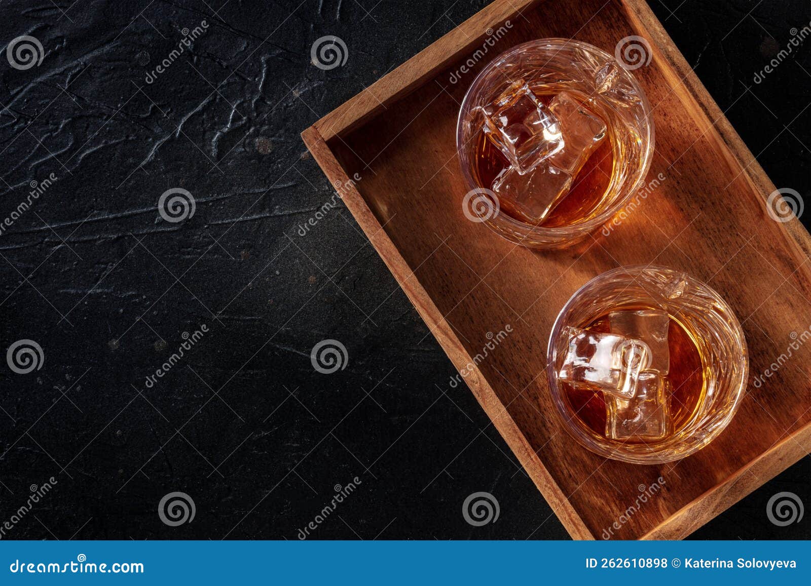 whiskey in glasses with ice. bourbon whisky on rocks on a black slate background