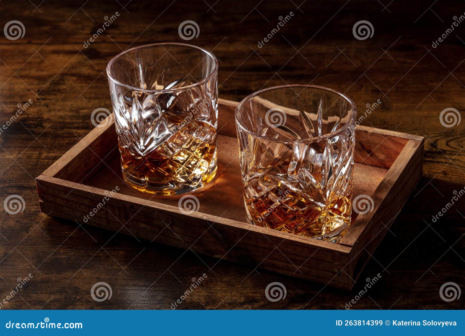 whiskey in glasses with ice. bourbon whisky on rocks on a dark rustic background