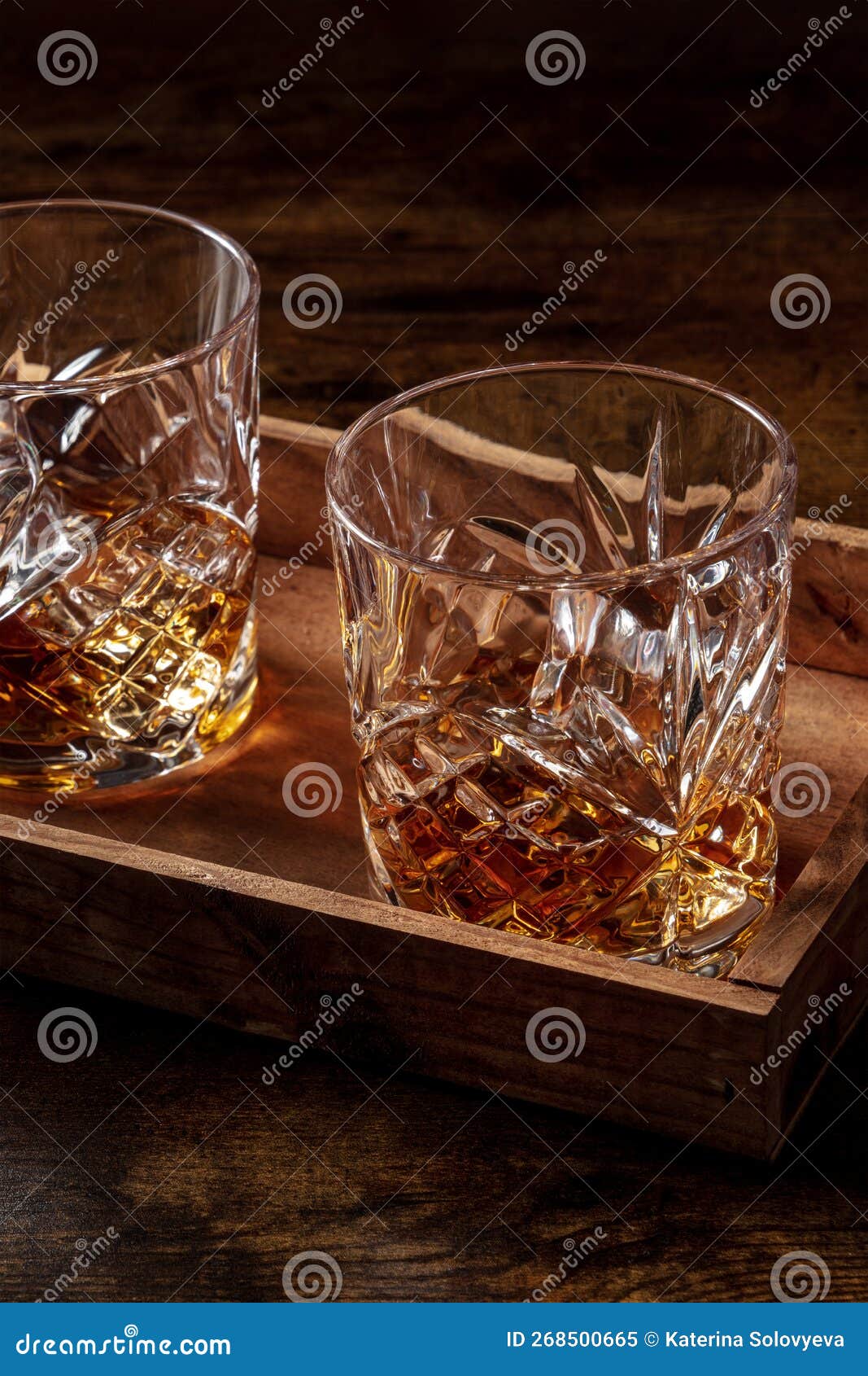 whiskey in glasses with ice. bourbon whisky on rocks on a dark wooden table