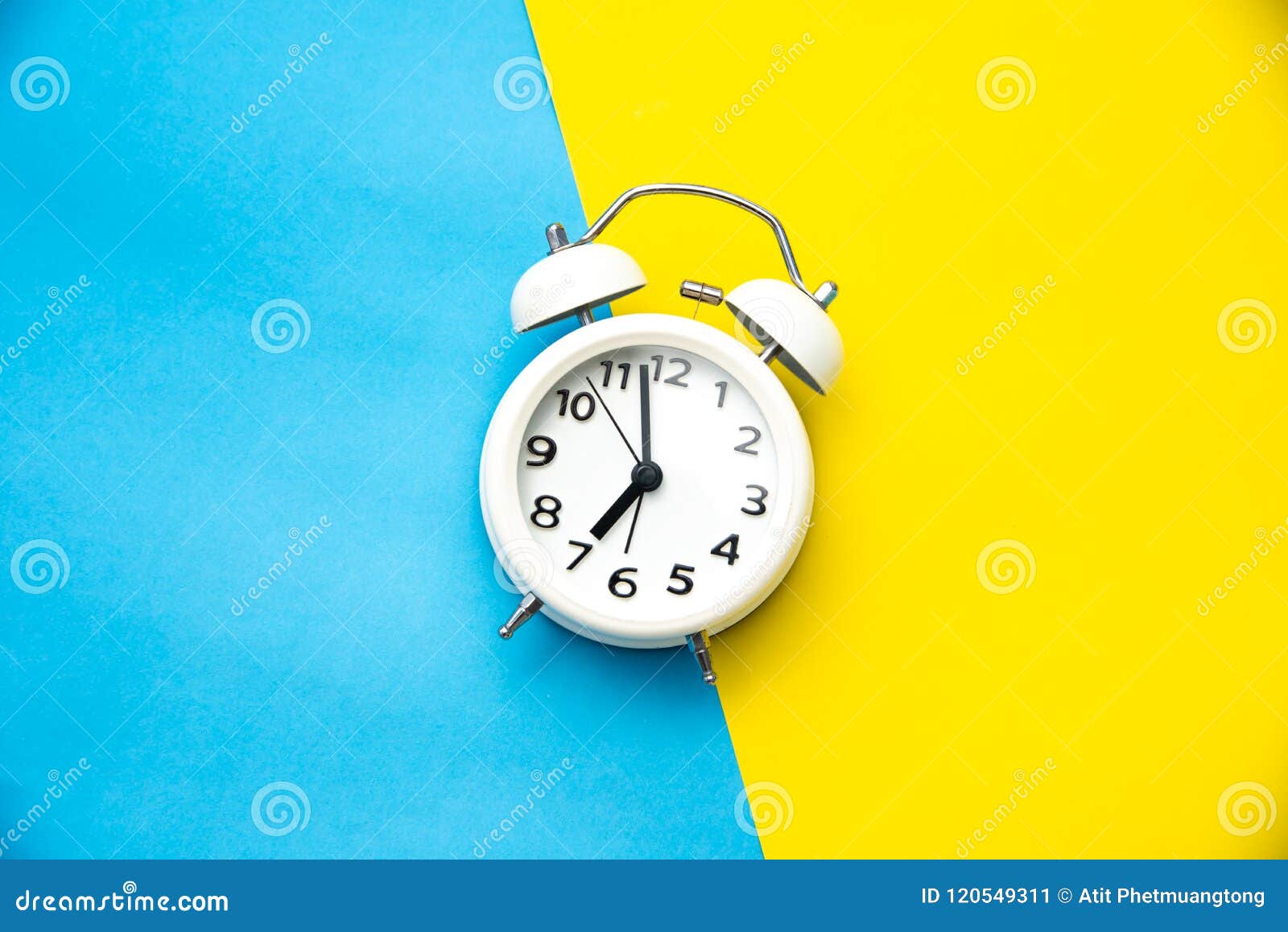 White Alarm Clock on Two Tone Color Yellow and Light Blue Background