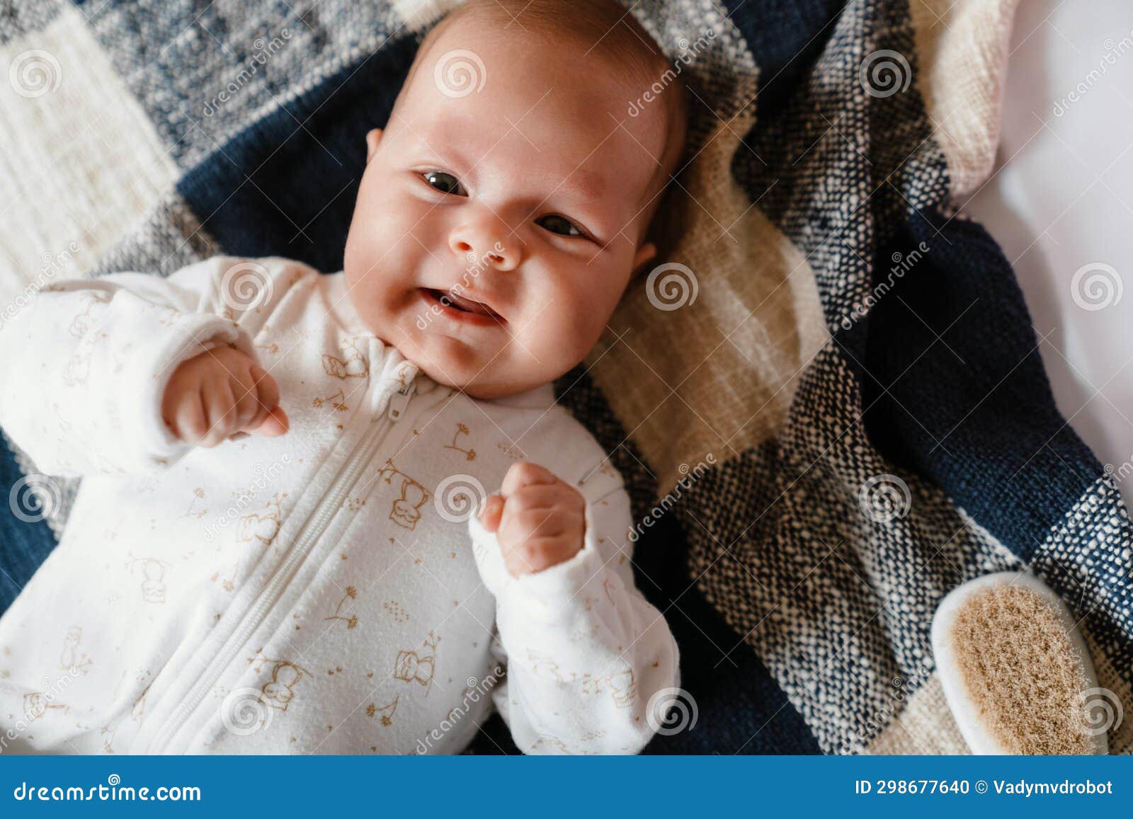 White Baby Wearing Romper Looking at Camera while Lying on Bed Stock