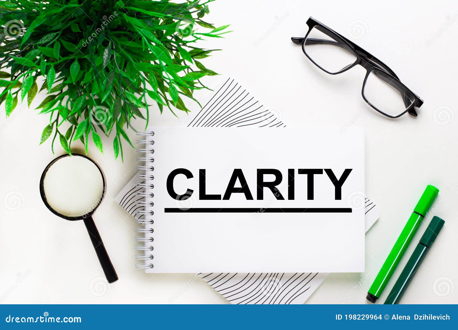 on a white background lies a notebook with the word clarity, glasses, a magnifying glass, green markers and a green plant