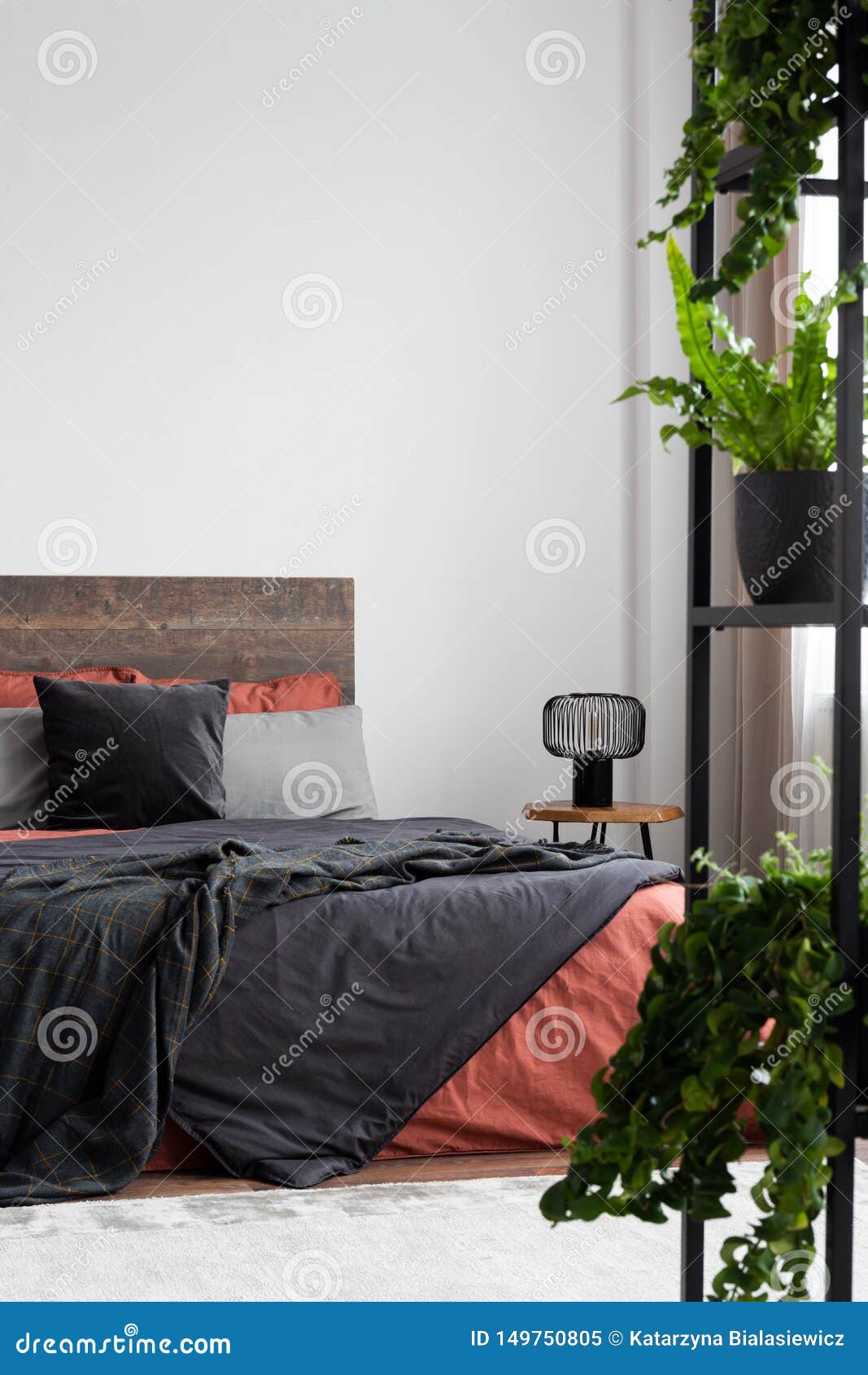 White Bedroom with Plants, Coral and Grey Bedding and Empty Wall Stock