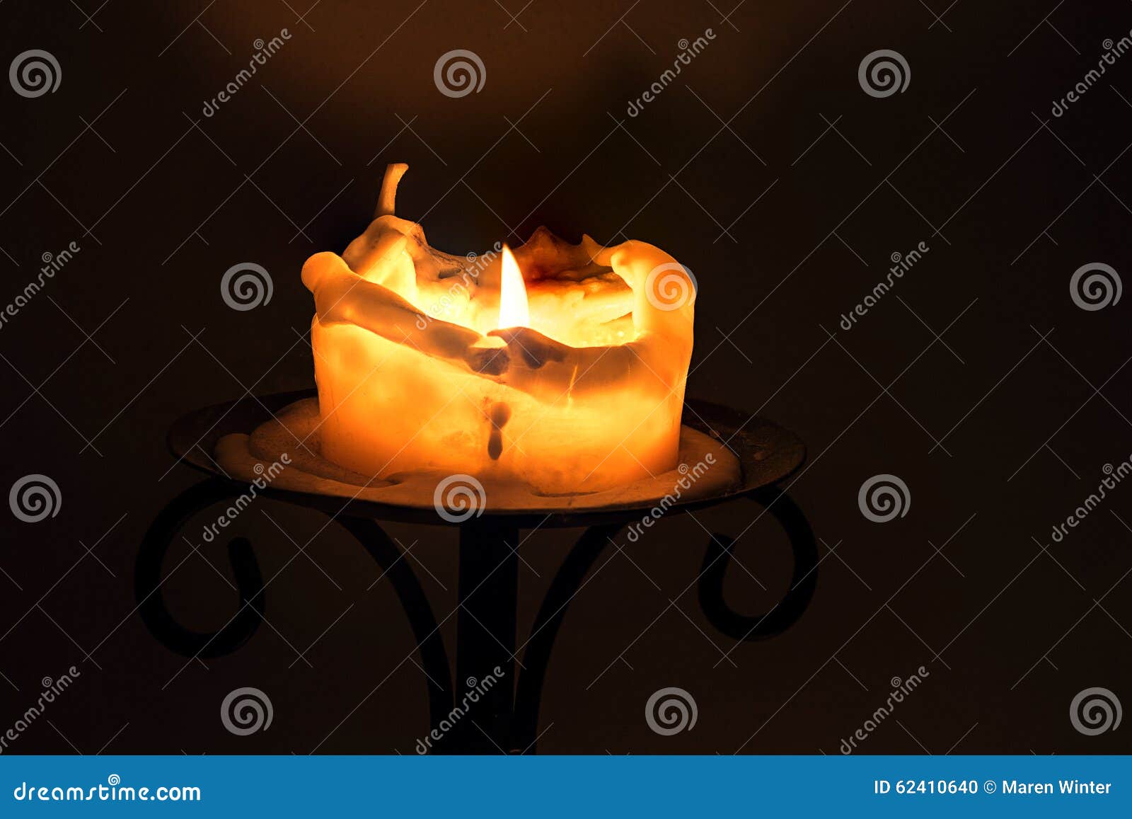 White Candle with Flame and Melting Wax on an Iron Candlestick a