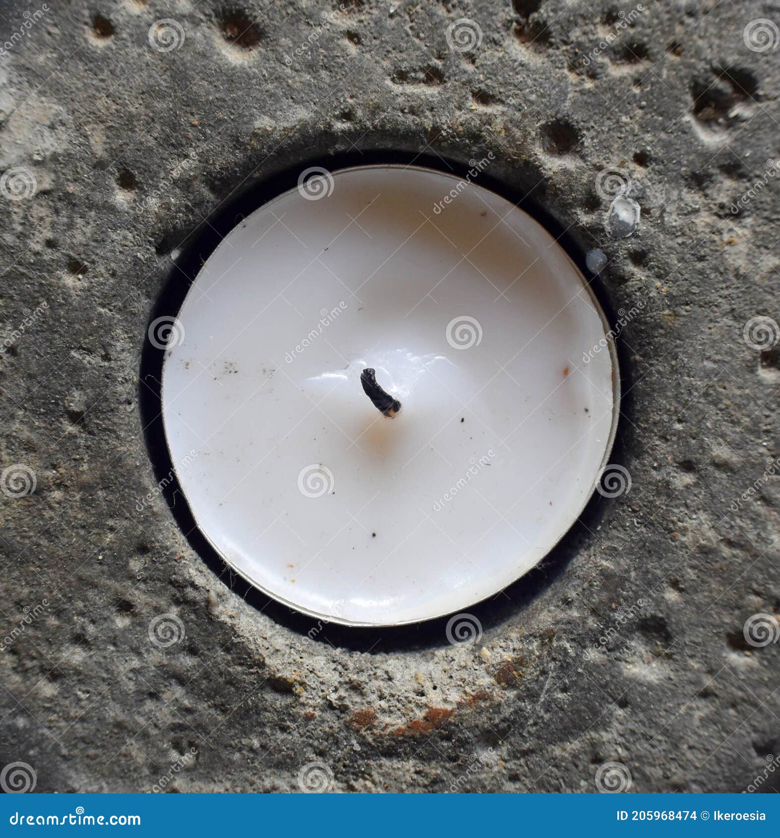 white candle in porous rock hole.