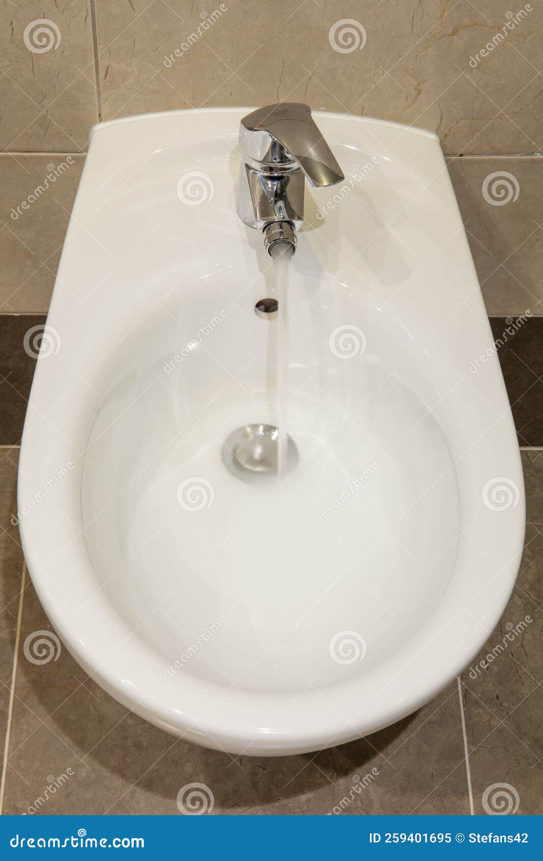 White Ceramic Bidet with a Running Water in Modern Bathroom.Close Up