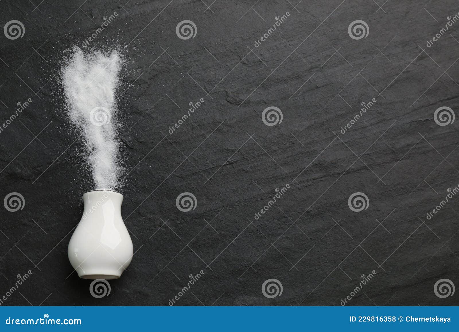 White Ceramic Salt Shaker on Black Table, Top View. Space for Text