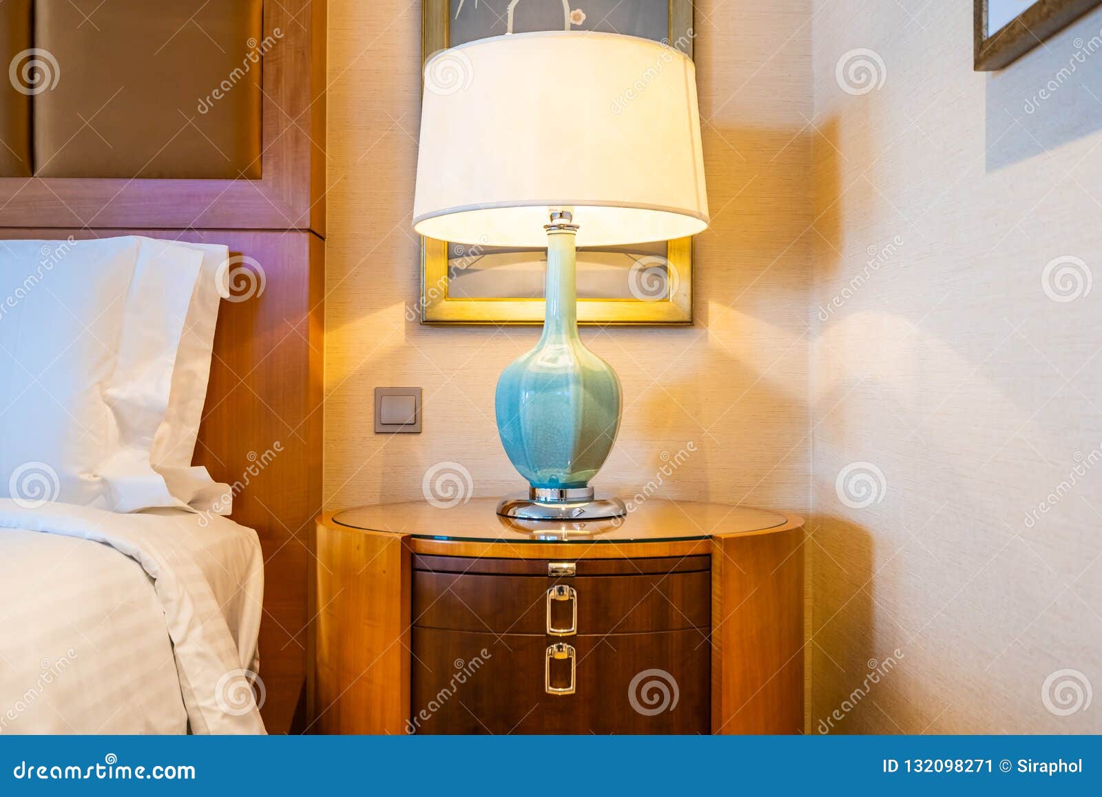 White Comfortable Pillow on Bed with Table Light Lamp Decoration Stock