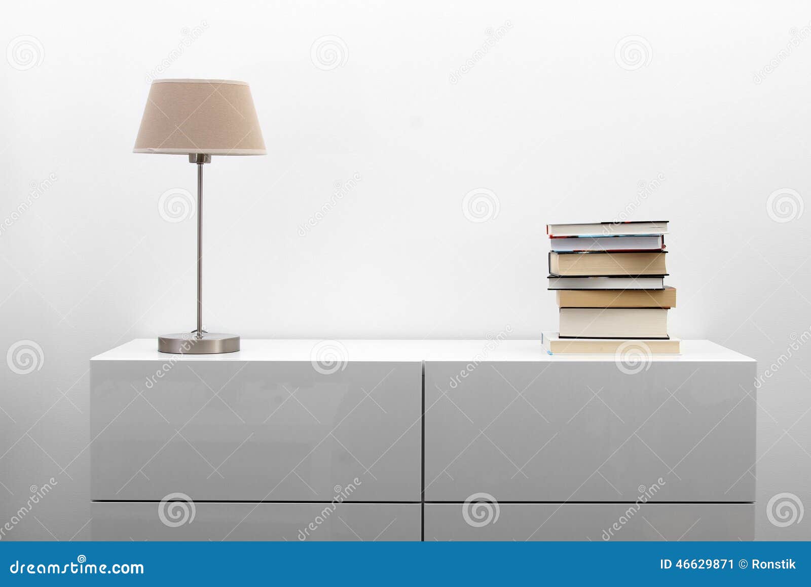 white commode with lamp and books in bright interior
