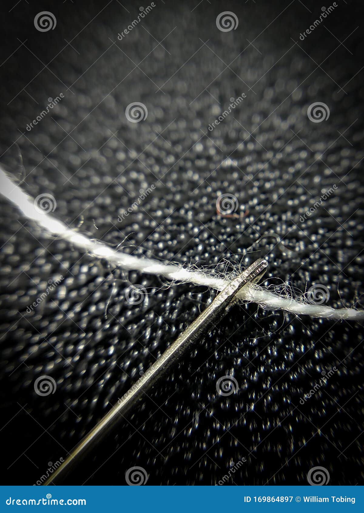 White Cotton Thread between Needle Hole on Black Abstract Background