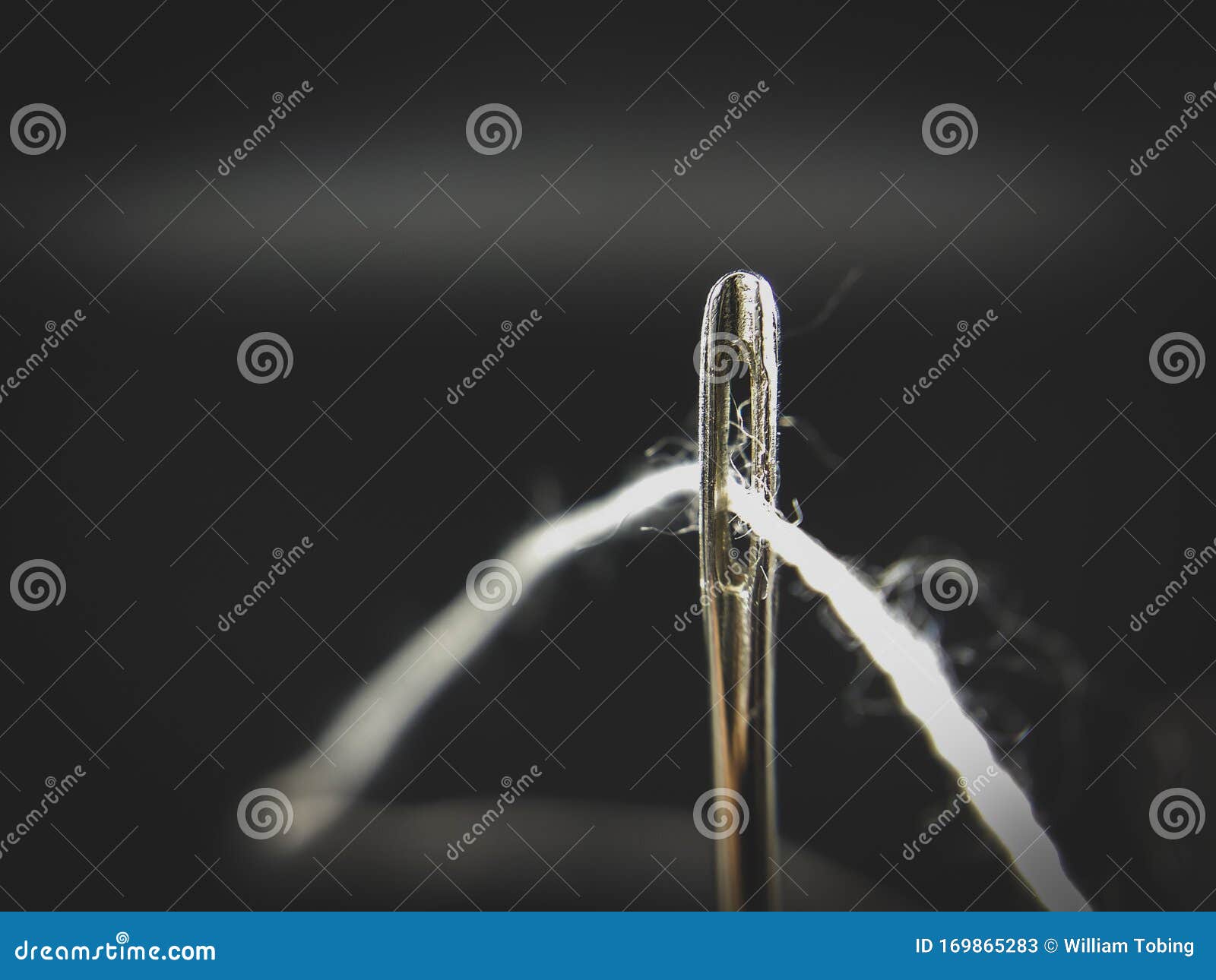 White Cotton Thread between Needle Hole on Black Abstract Background