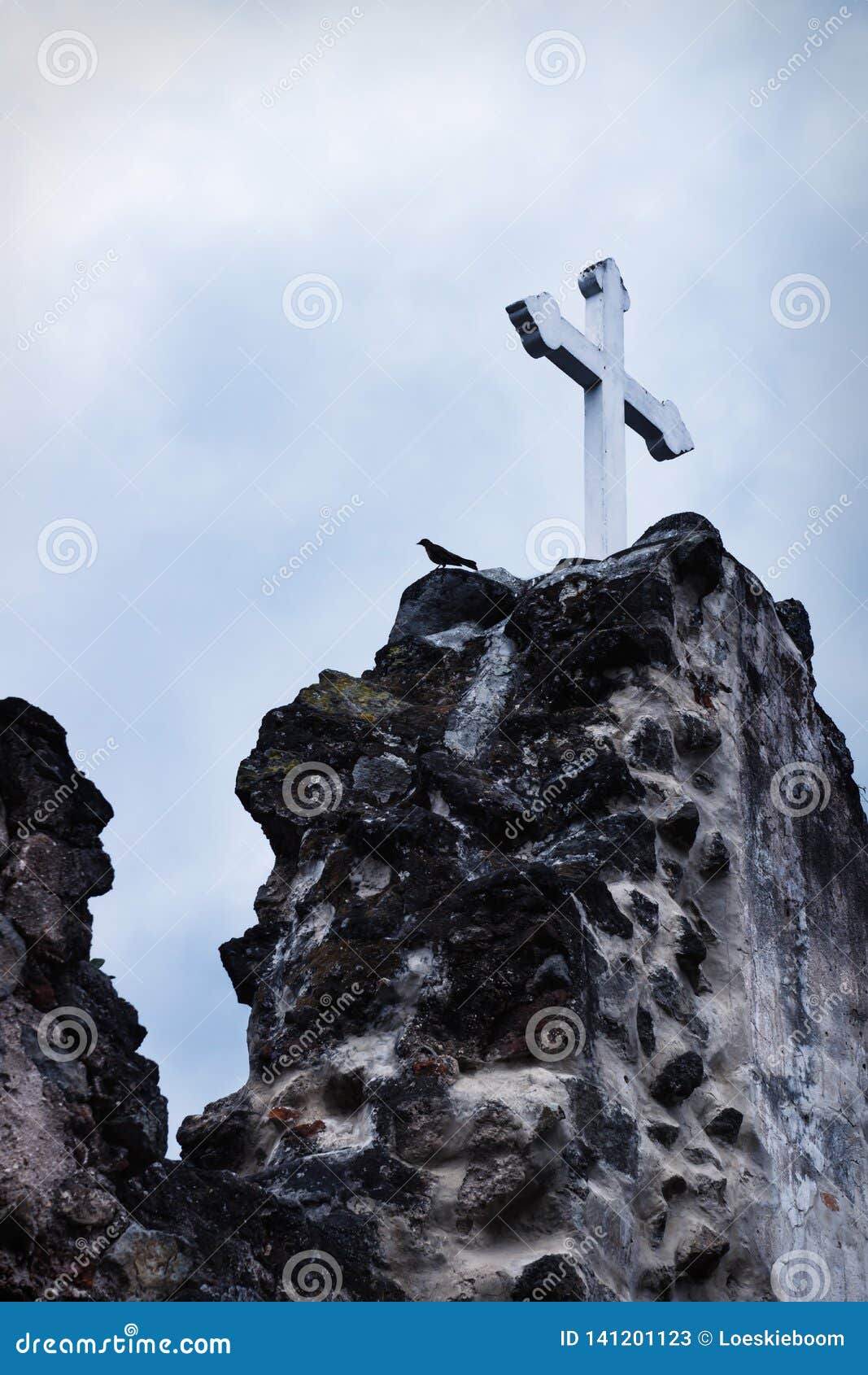white cross on stone ruins with dramatic sky in hermano pedro, antigua, guatemala
