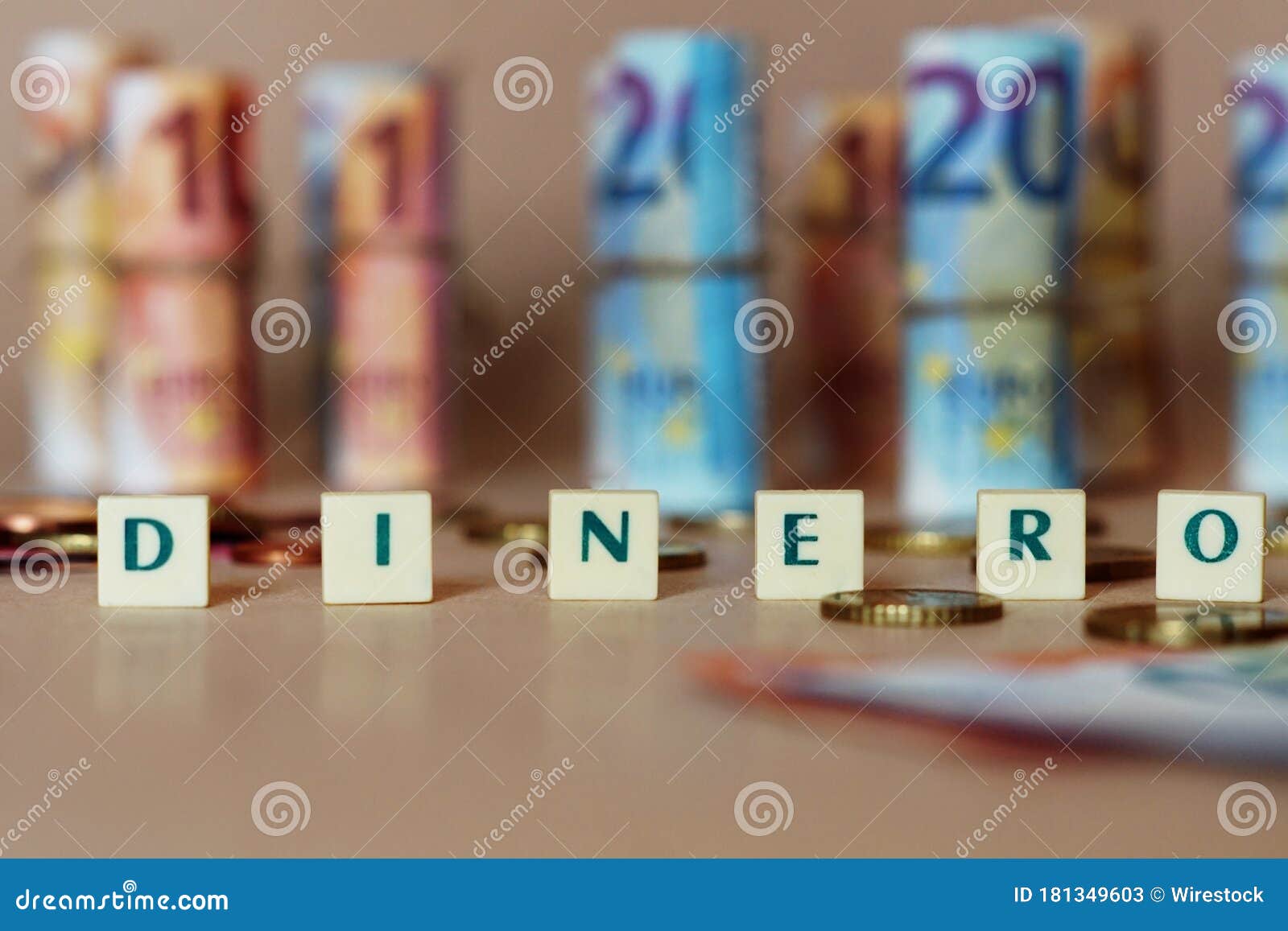 cubes spelling dinero in front of spanish dinero bills and coins on the table