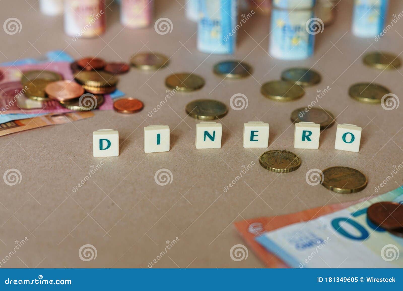 cubes spelling dinero in front of spanish dinero bills and coins on the table