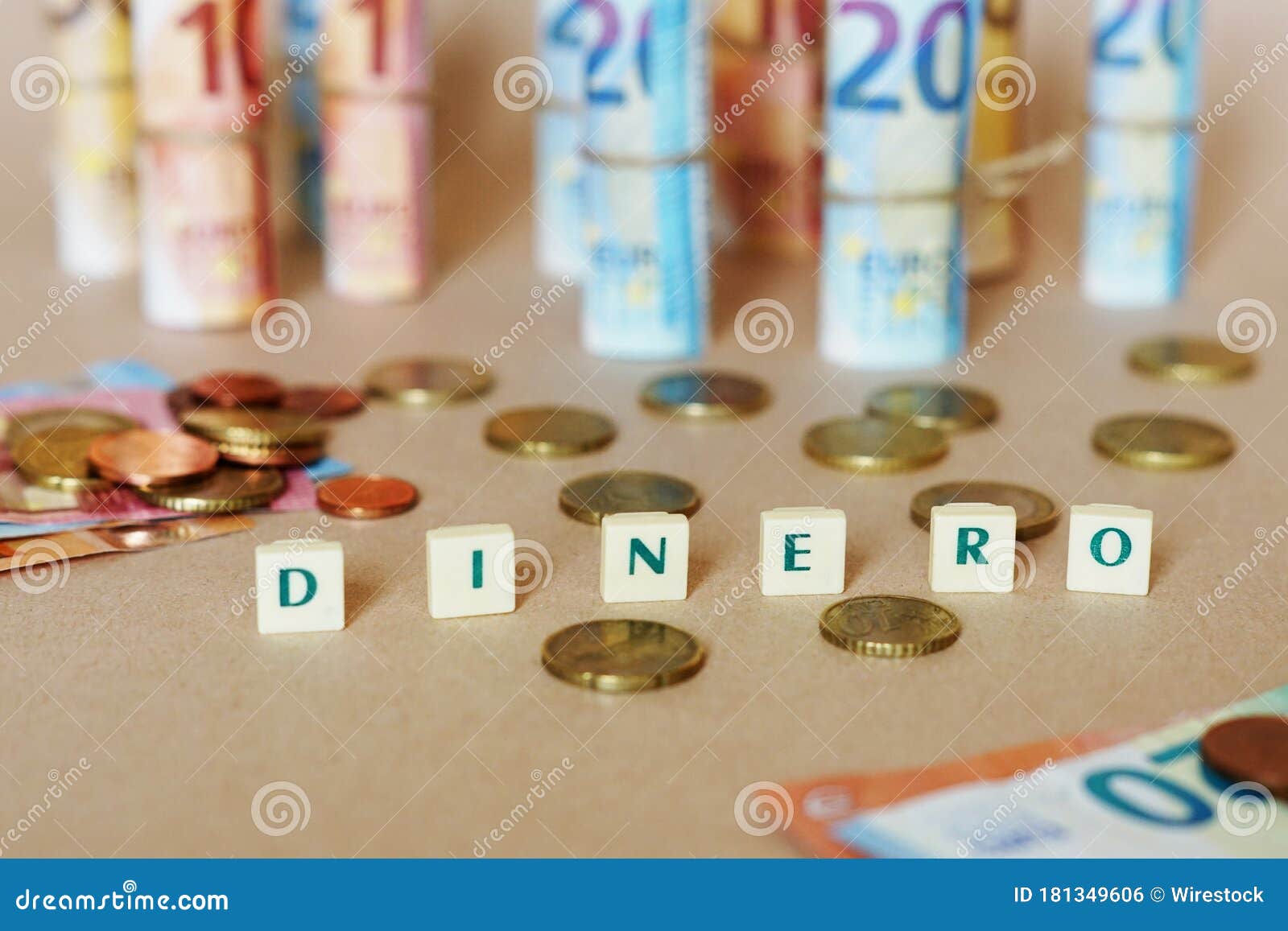 cubes spelling dinero in front of spanish dinero bills and coins on the table