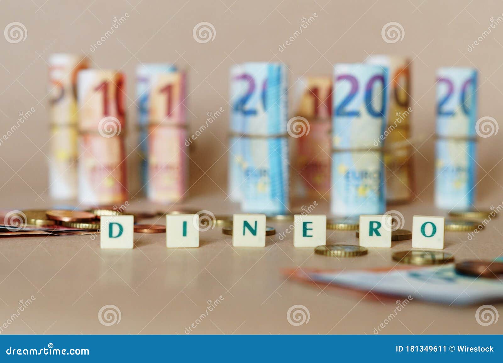 cubes spelling dinero in front of spanish dinero bills and coins on the table
