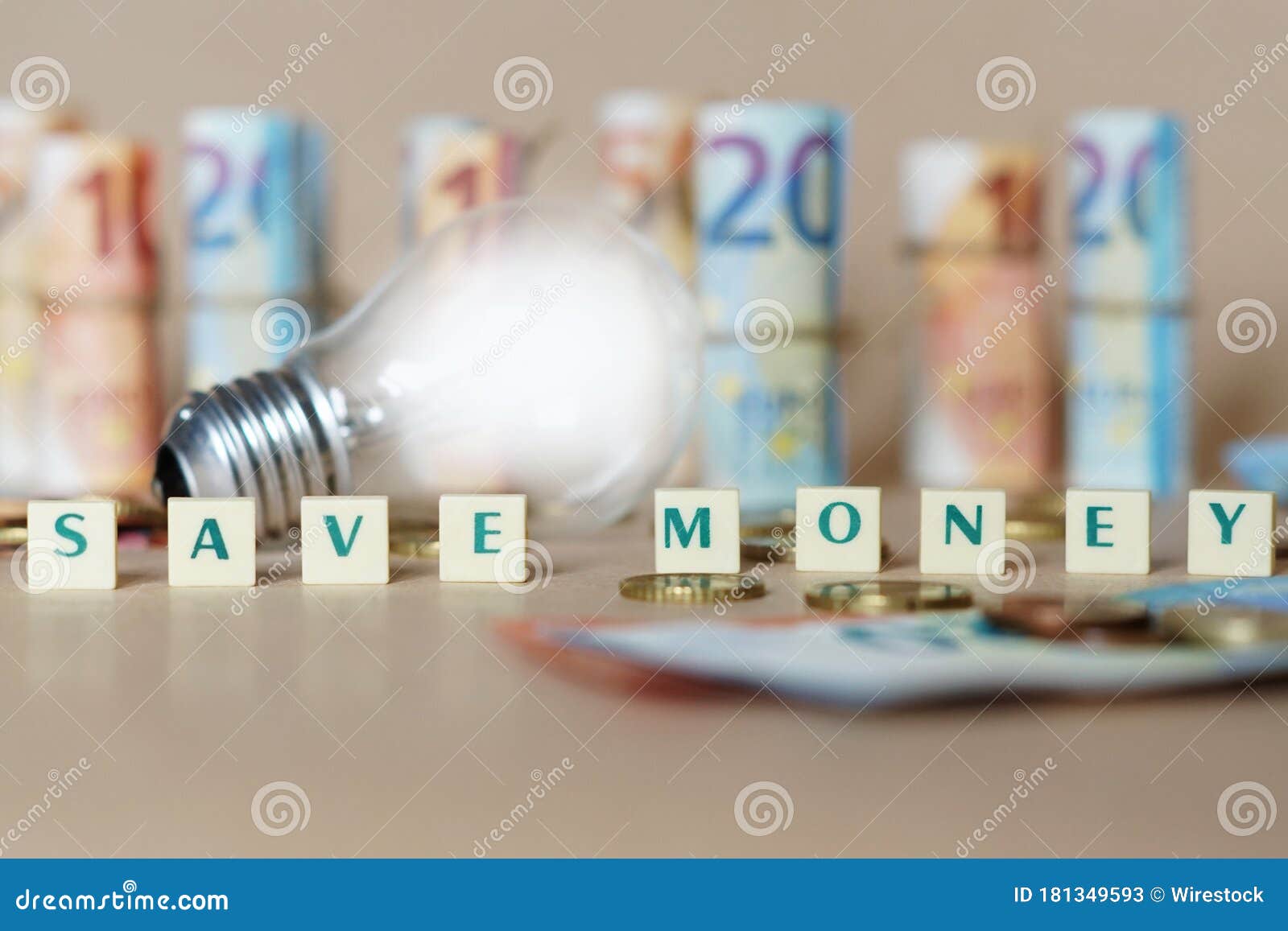 cubes spelling save money on the table with an illuminated light bulb and dinero bills