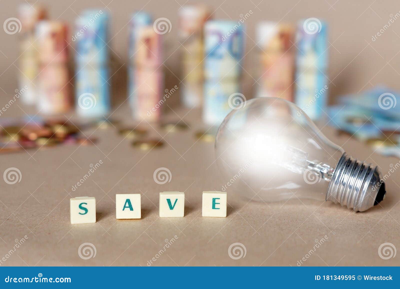 cubes spelling save money on the table with an illuminated light bulb and dinero bills