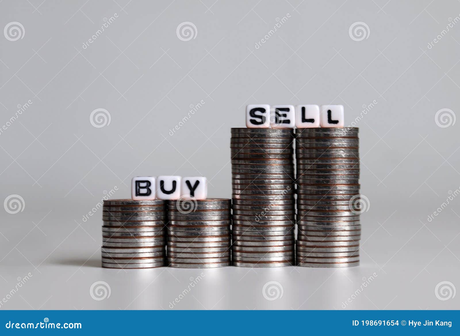 white cubes with the words buy sell on pile of coins in the  of a graph.