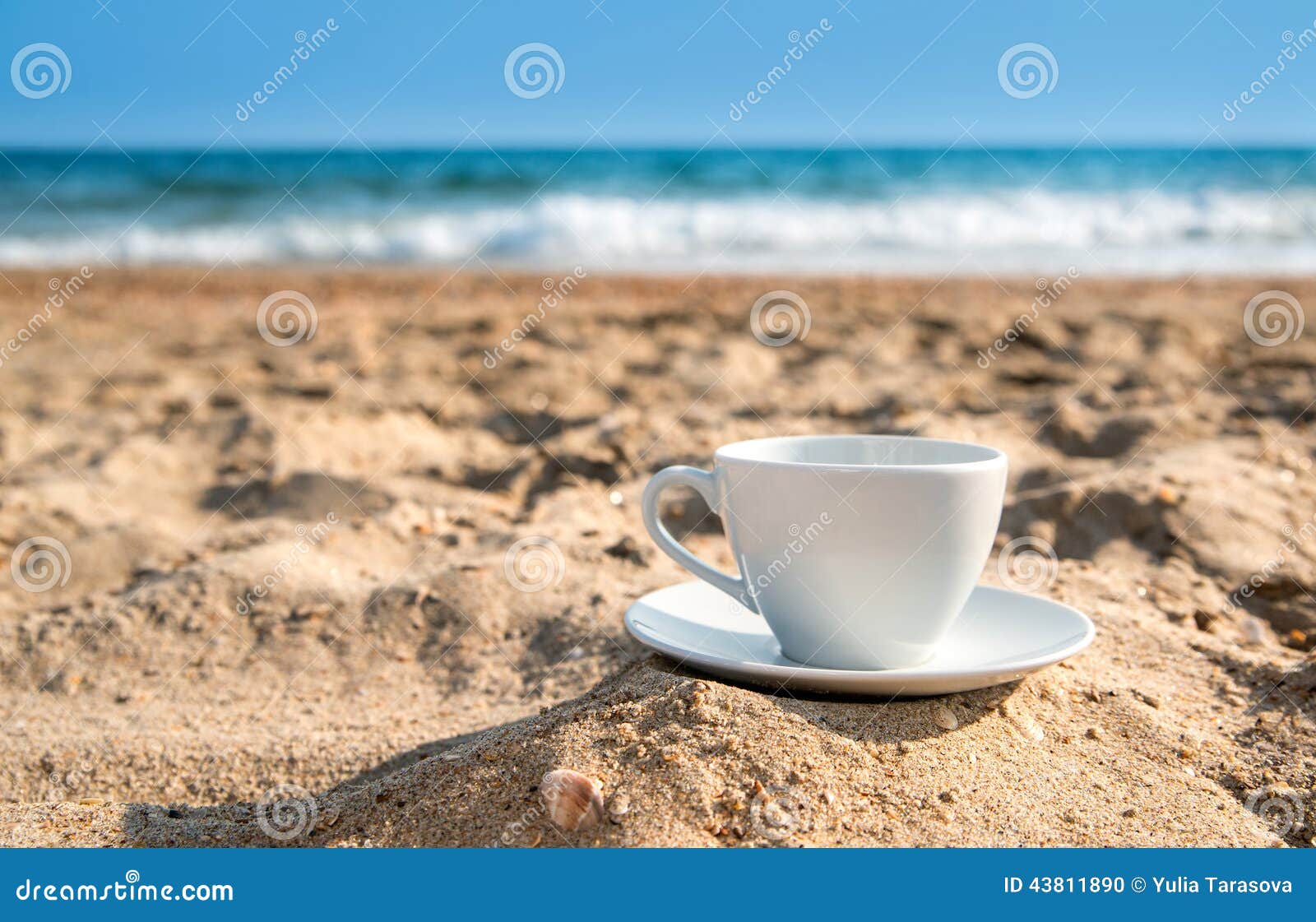 White Cup with Tea or Coffee on Sand Beach Front of Sea Stock Photo