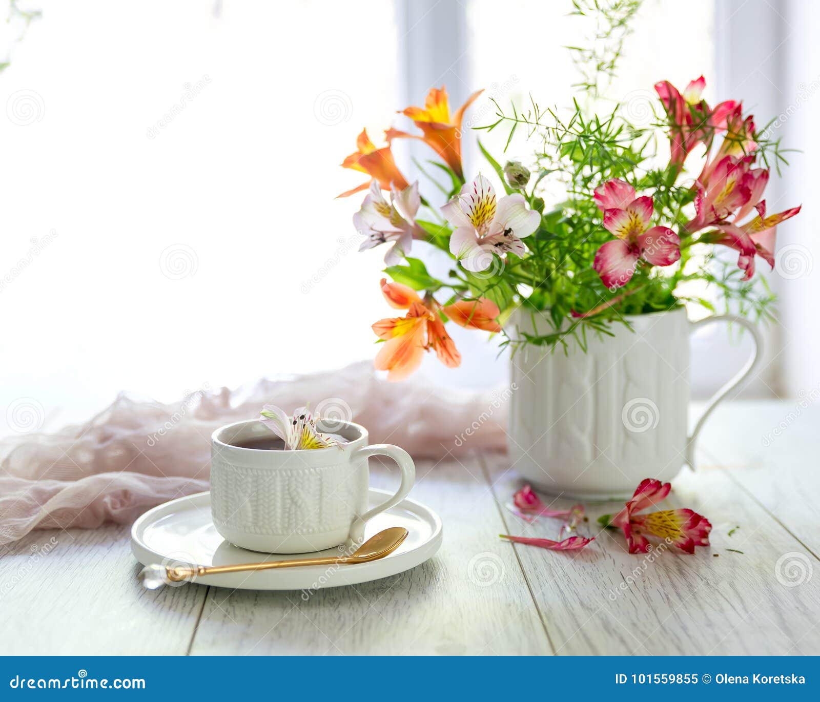 white cup with tea on the table. flowers nearby