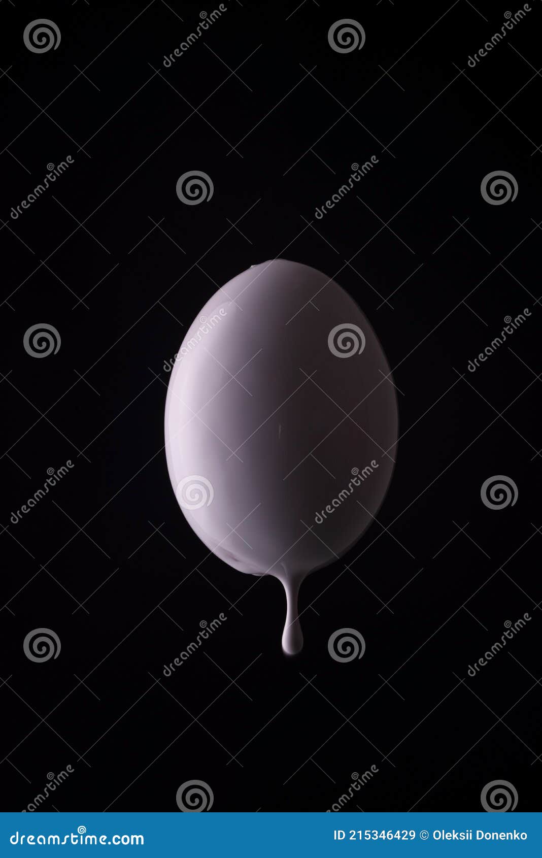 White Egg Dripping with Drops of White Paint on a Black Background