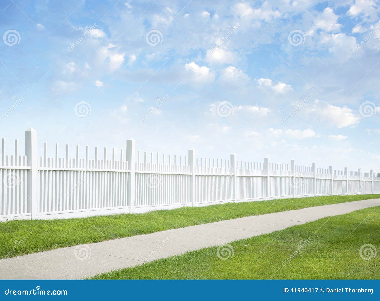 white fence, grass, sidewalk, blue sky and clouds