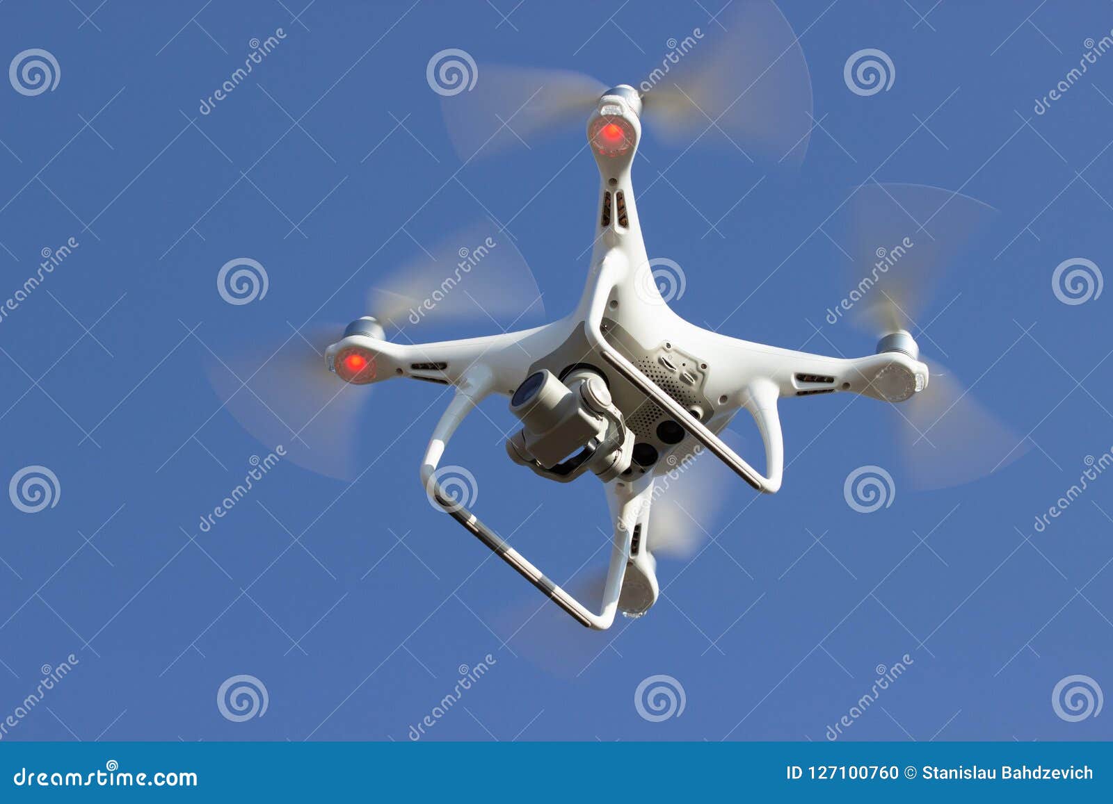 white flying dron with camera on blue sky background