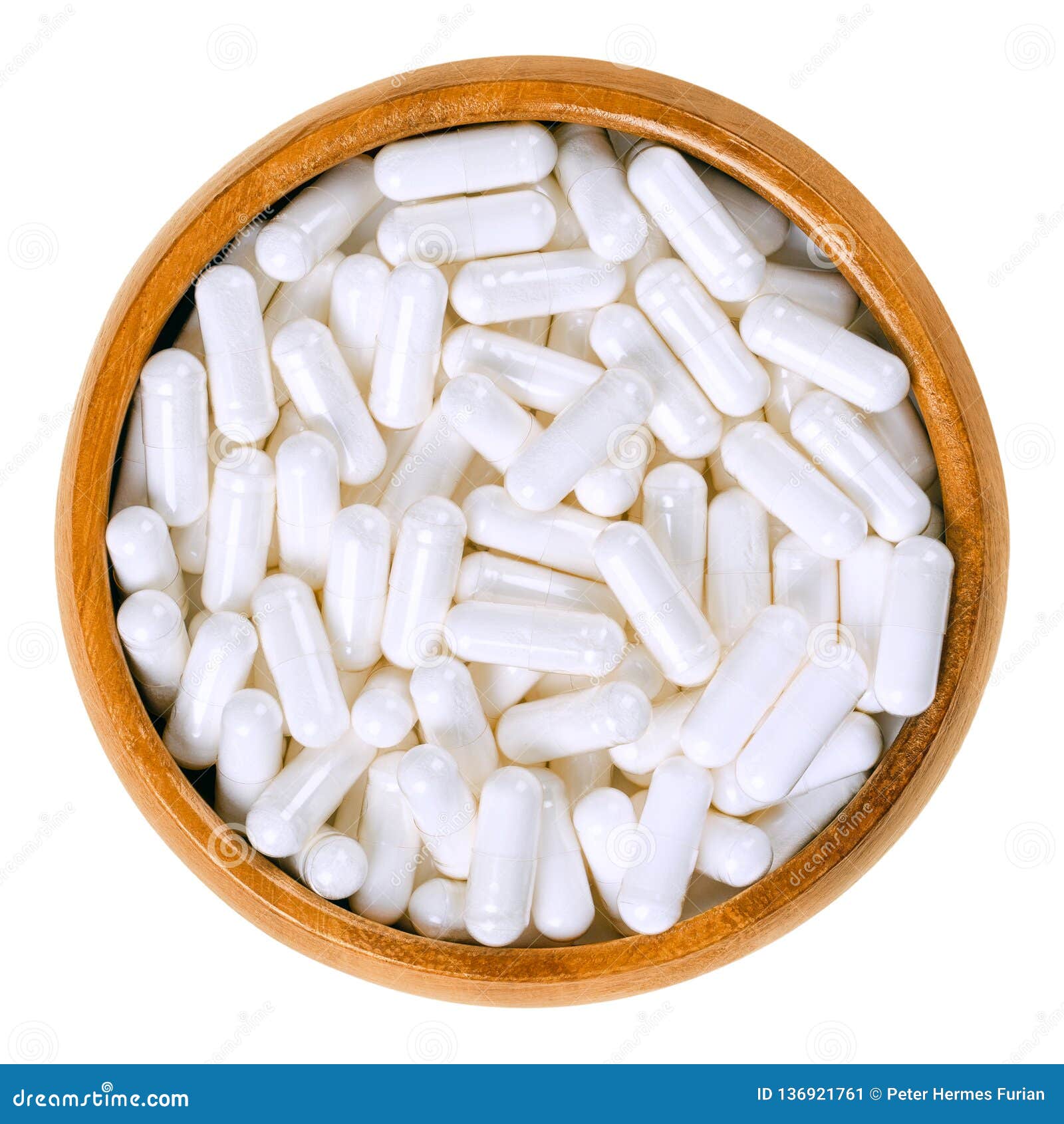 white food supplement capsules in wooden bowl over white